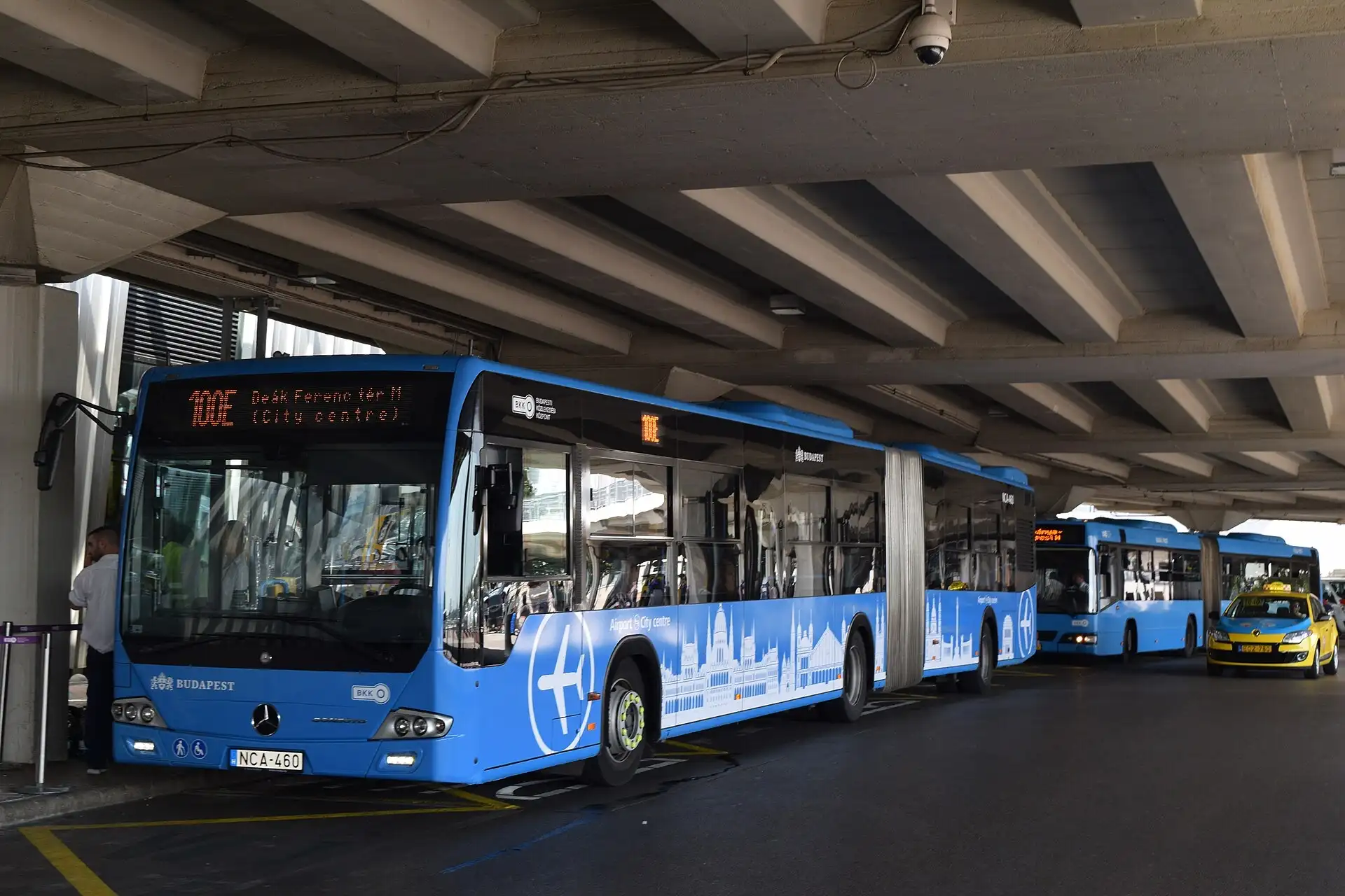 The blue 100E Airport Express bus waiting at Budapest airport, its sign reading Deák Ferenc tér, city centre