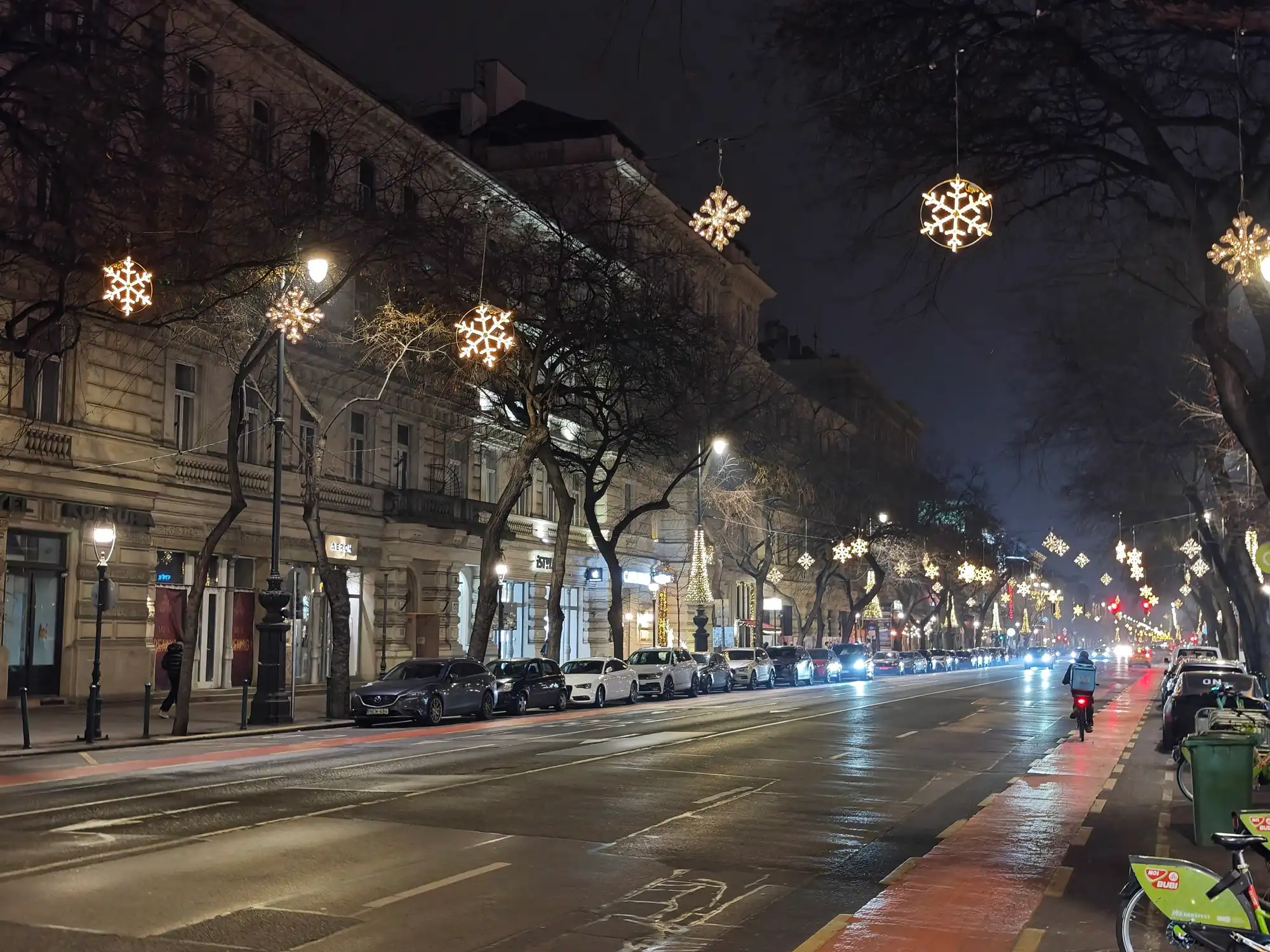 Andrássy út at night in December, with white snowflake lights hanging in the bare plane trees along both sides of the avenue
