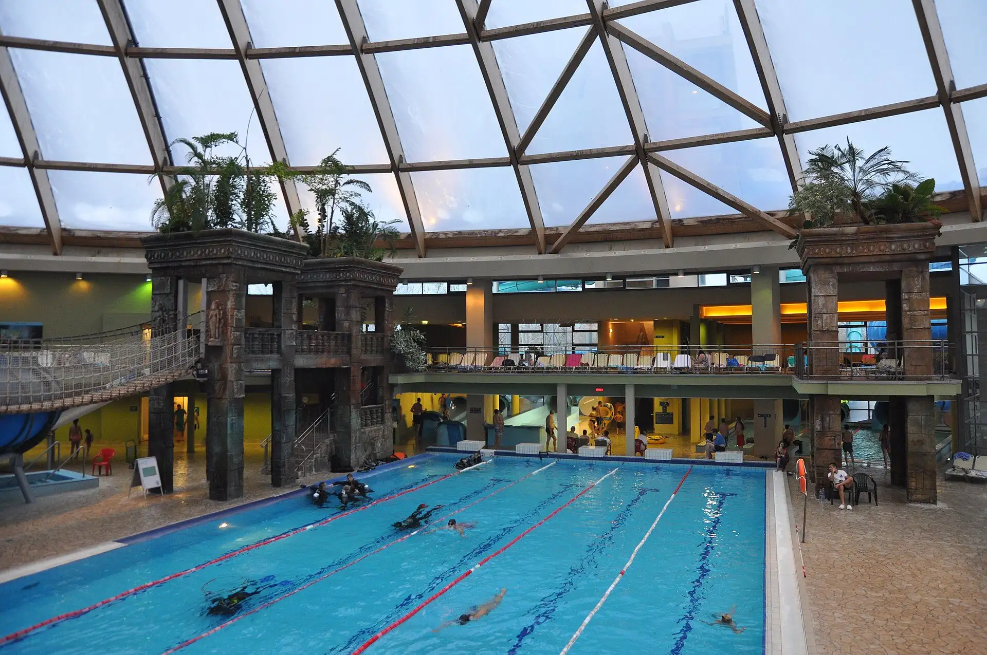 The indoor 25-metre swimming pool at Aquaworld under the dome, with divers training in one lane and the temple behind