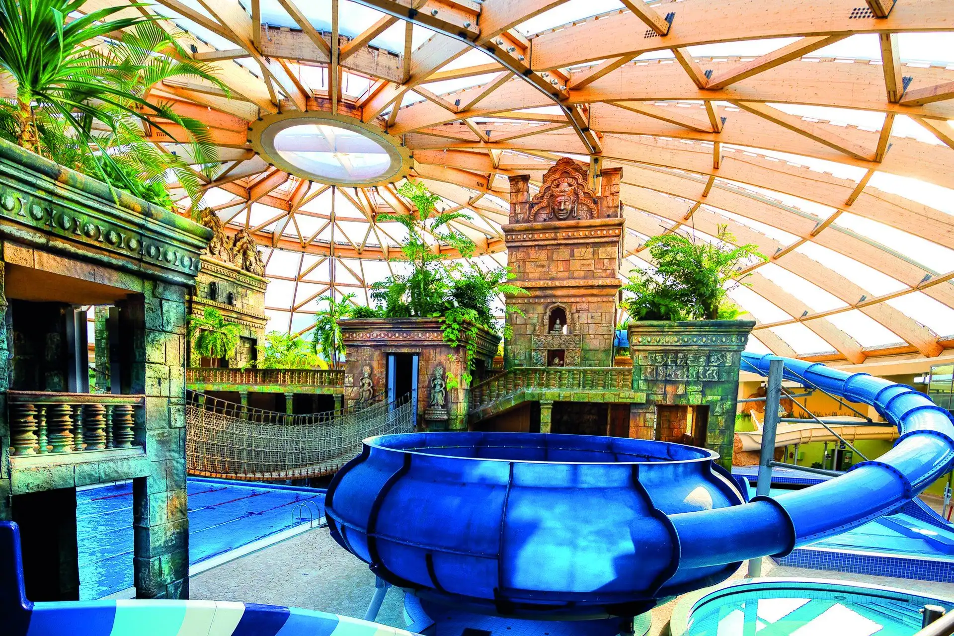 The blue bowl of the Onion slide at Aquaworld, with the temple, a rope bridge and tropical plants behind it