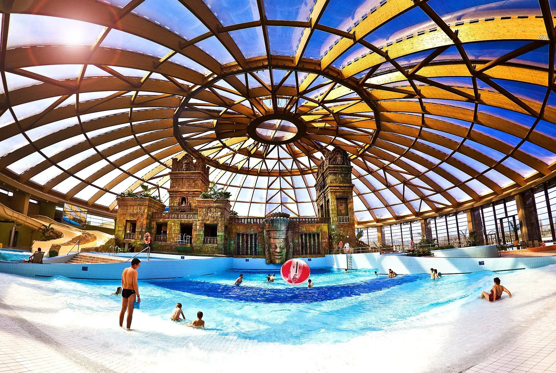 Swimmers in the shallow end of the wave pool at Aquaworld as a wave rolls in, the temple and the dome behind