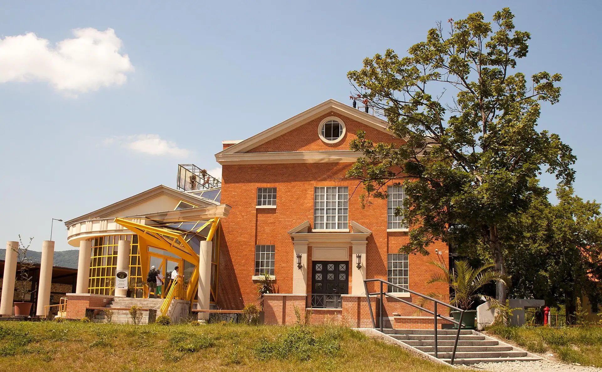 The red brick main exhibition building of the Aquincum Museum, a converted electricity substation, with its yellow steel entrance canopy