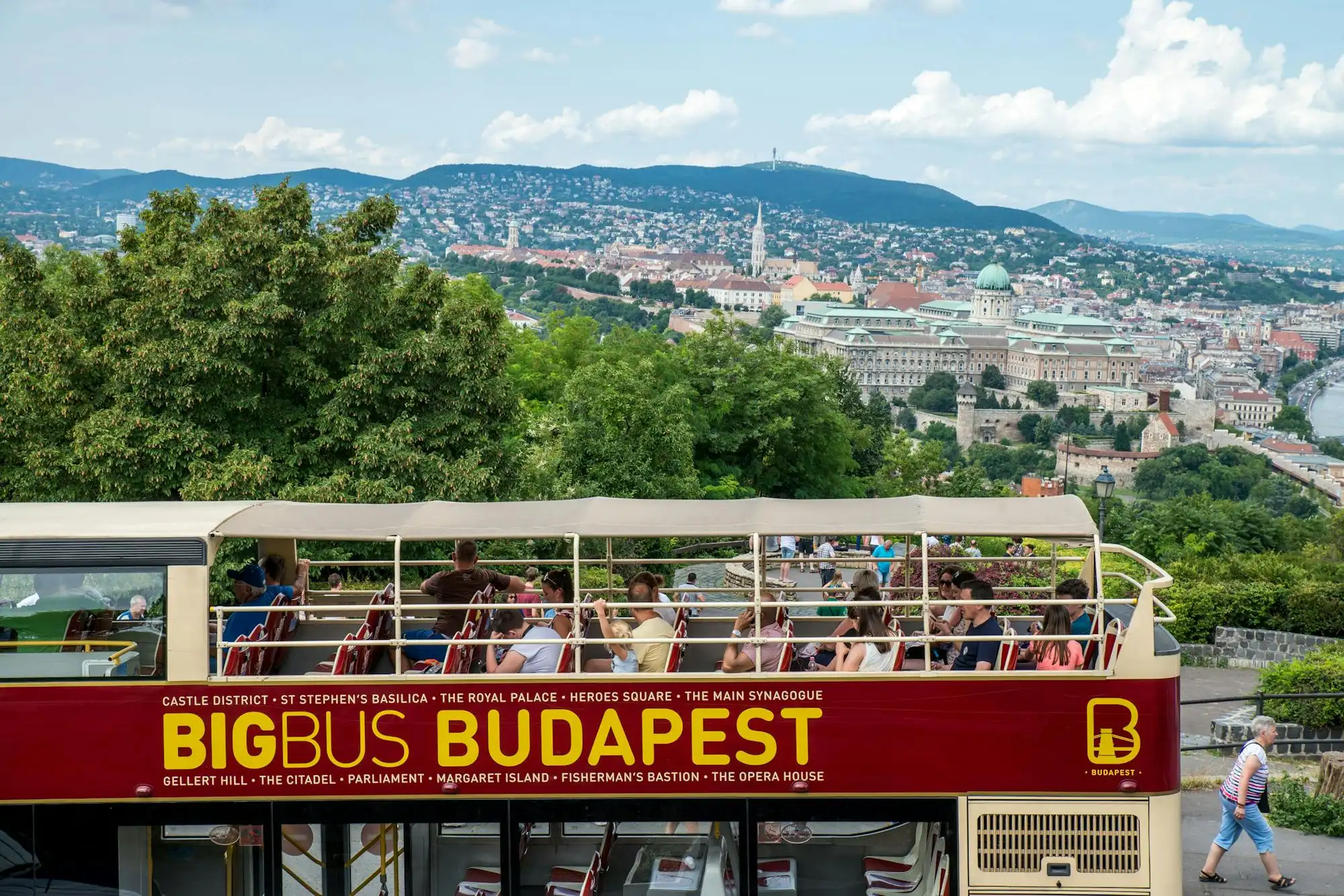 A Big Bus Budapest double-decker on Gellért Hill with Buda and the Danube behind