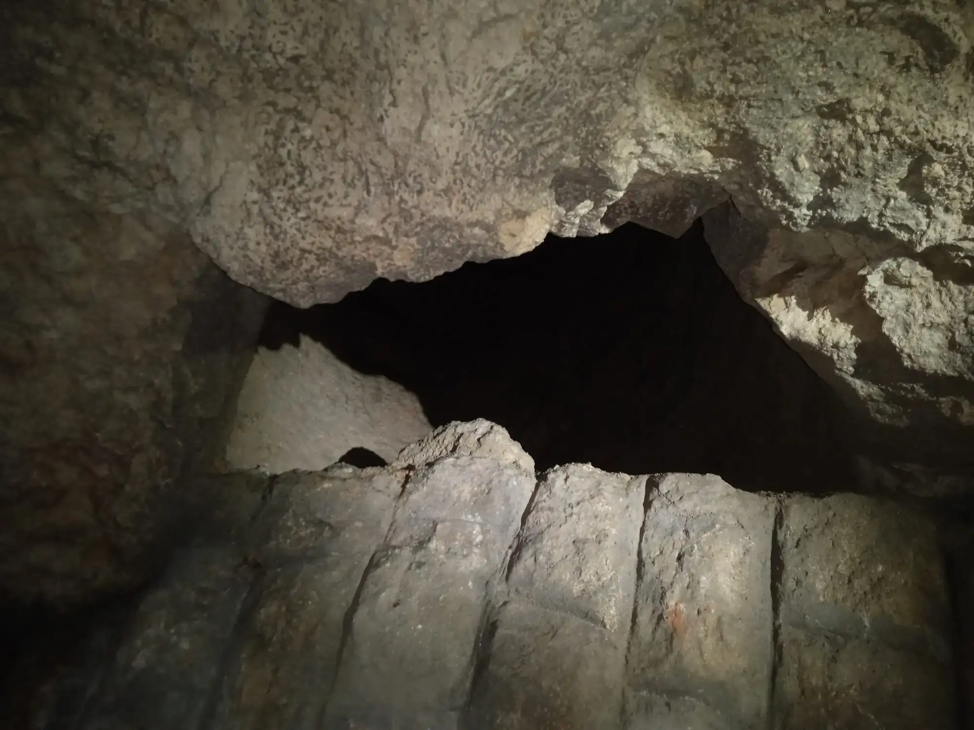 A natural rock arch between two pale limestone chambers of the Buda Castle Cave