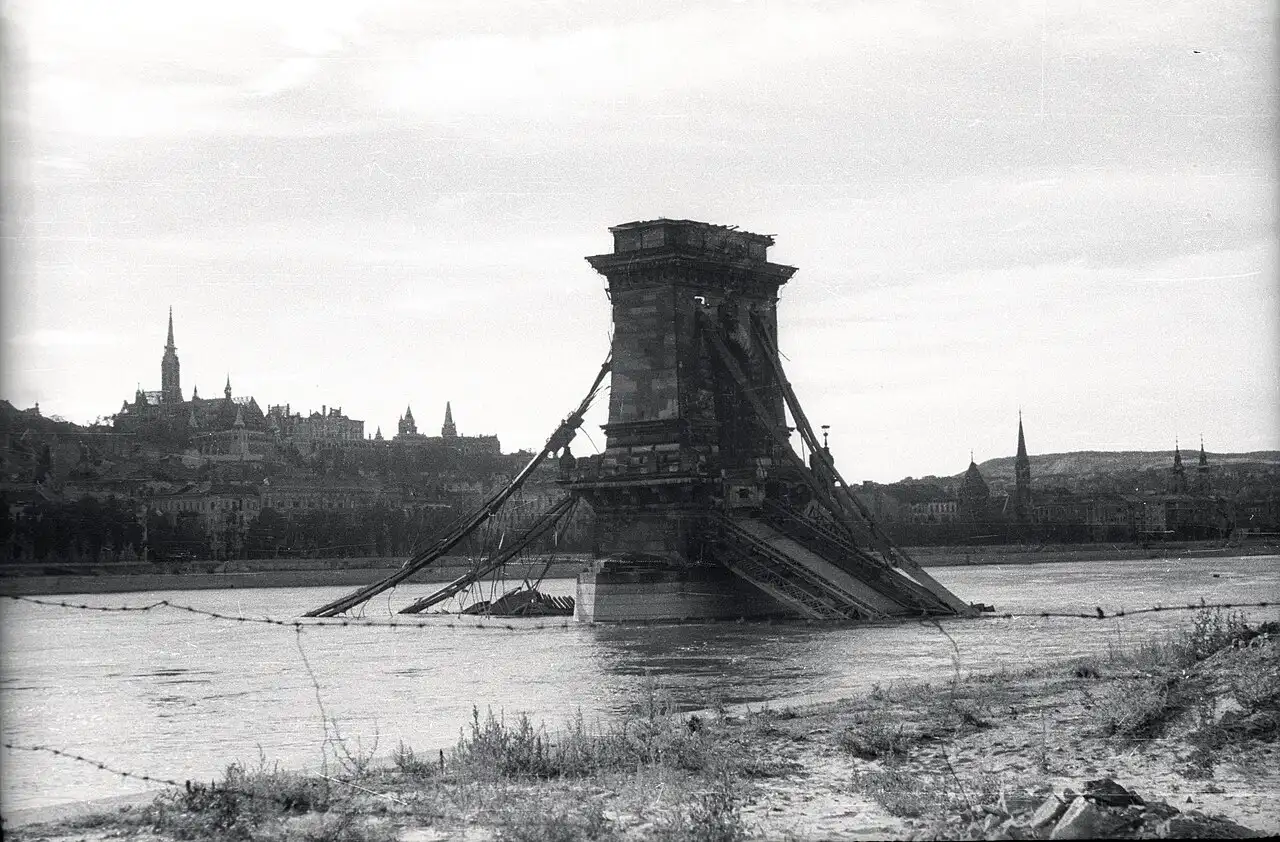 The Chain Bridge in 1945, one river pier still standing with the broken chains hanging into the Danube and the deck gone, Matthias Church and Fisherman's Bastion on Castle Hill behind