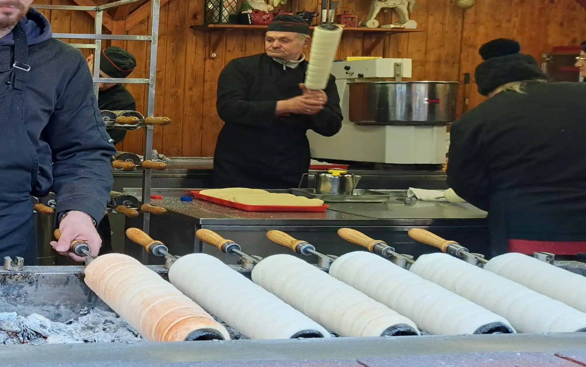 Kürtőskalács, chimney cakes, baking on wooden spits over hot coals at a stall at the Advent Bazilika market