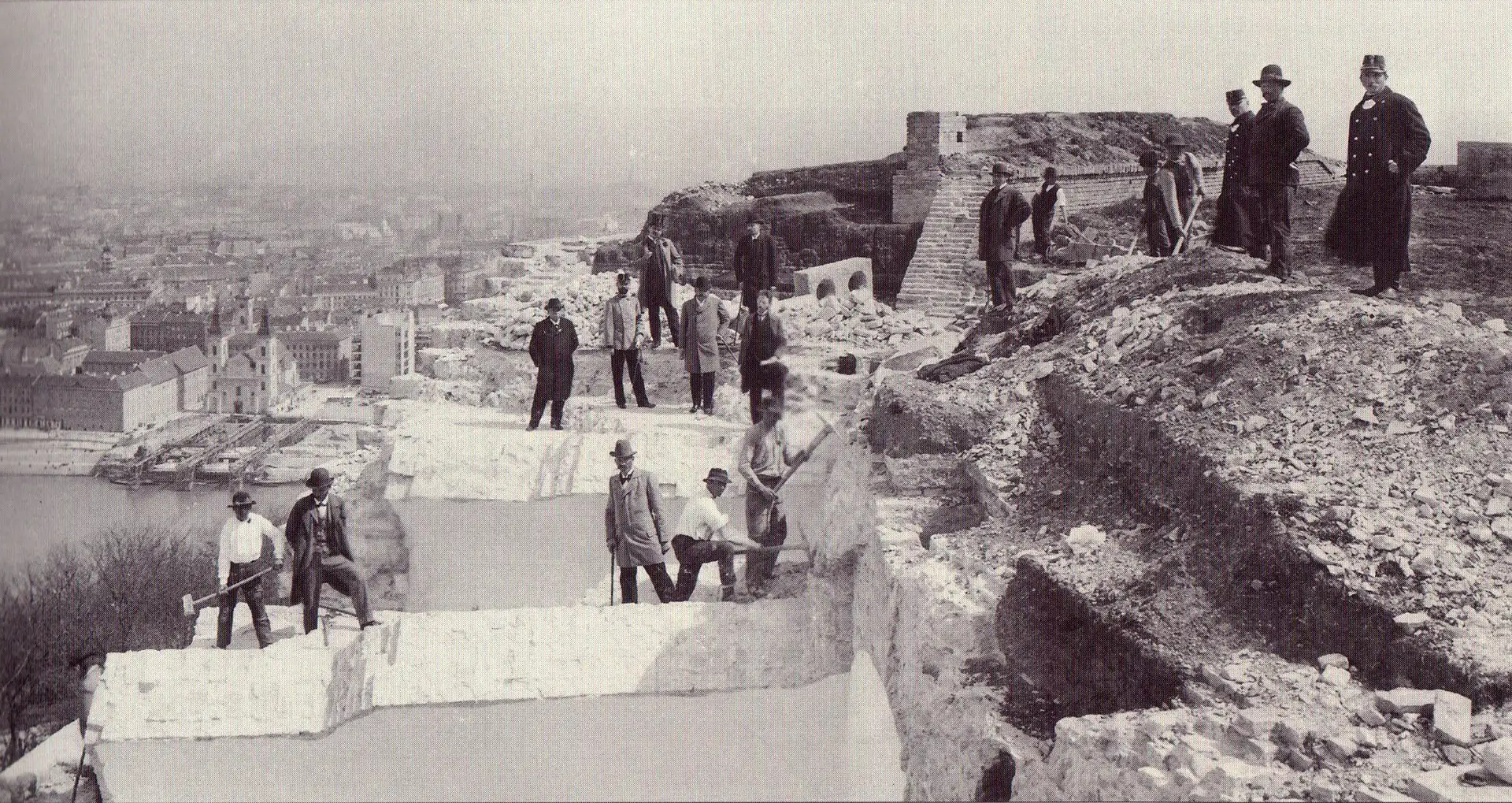 Men standing among the broken stone of the Citadella's walls above Budapest during the partial demolition at the end of the 1890s