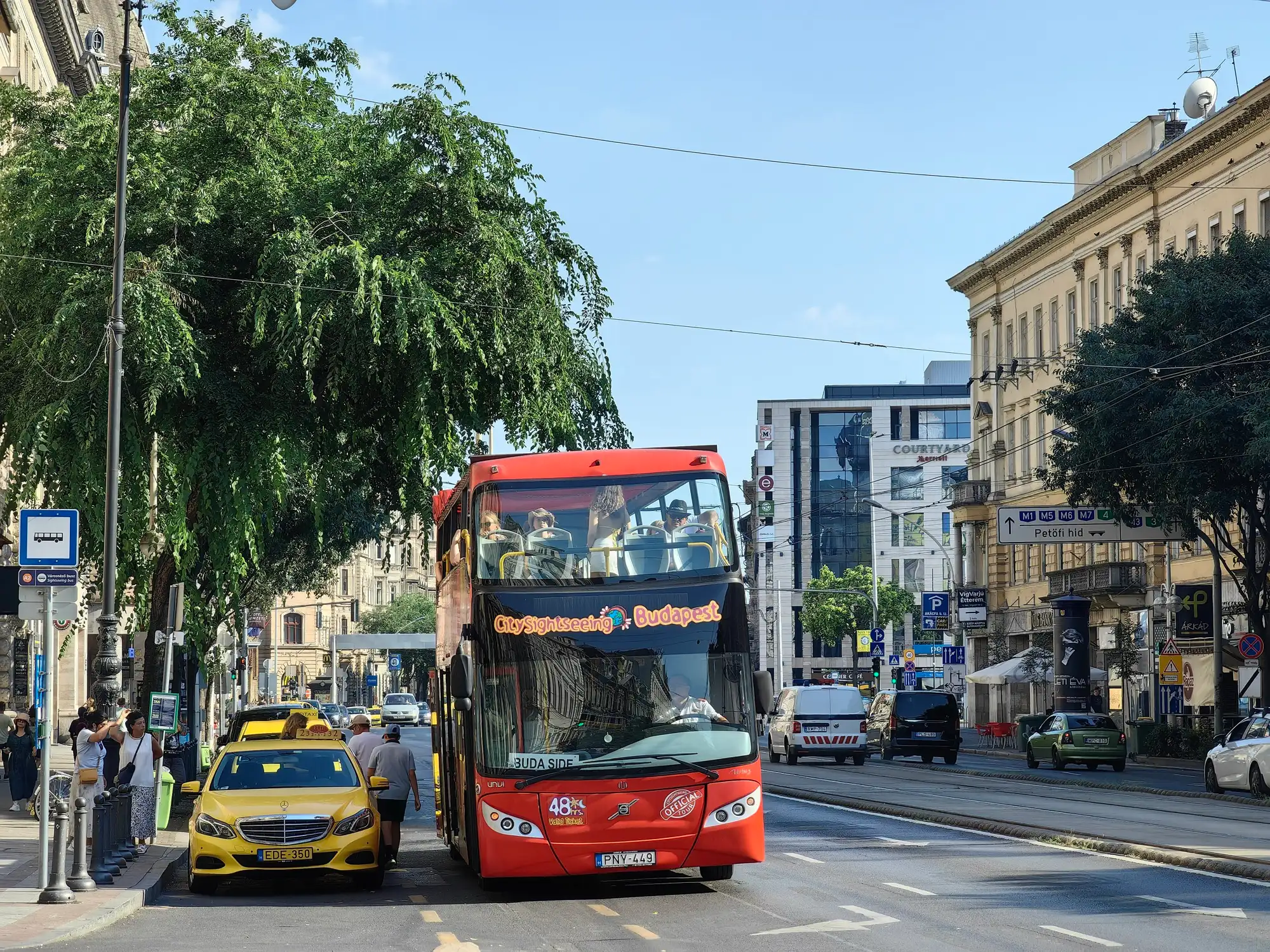 A red City Sightseeing Budapest open-top double-decker waiting at a stop in central Budapest