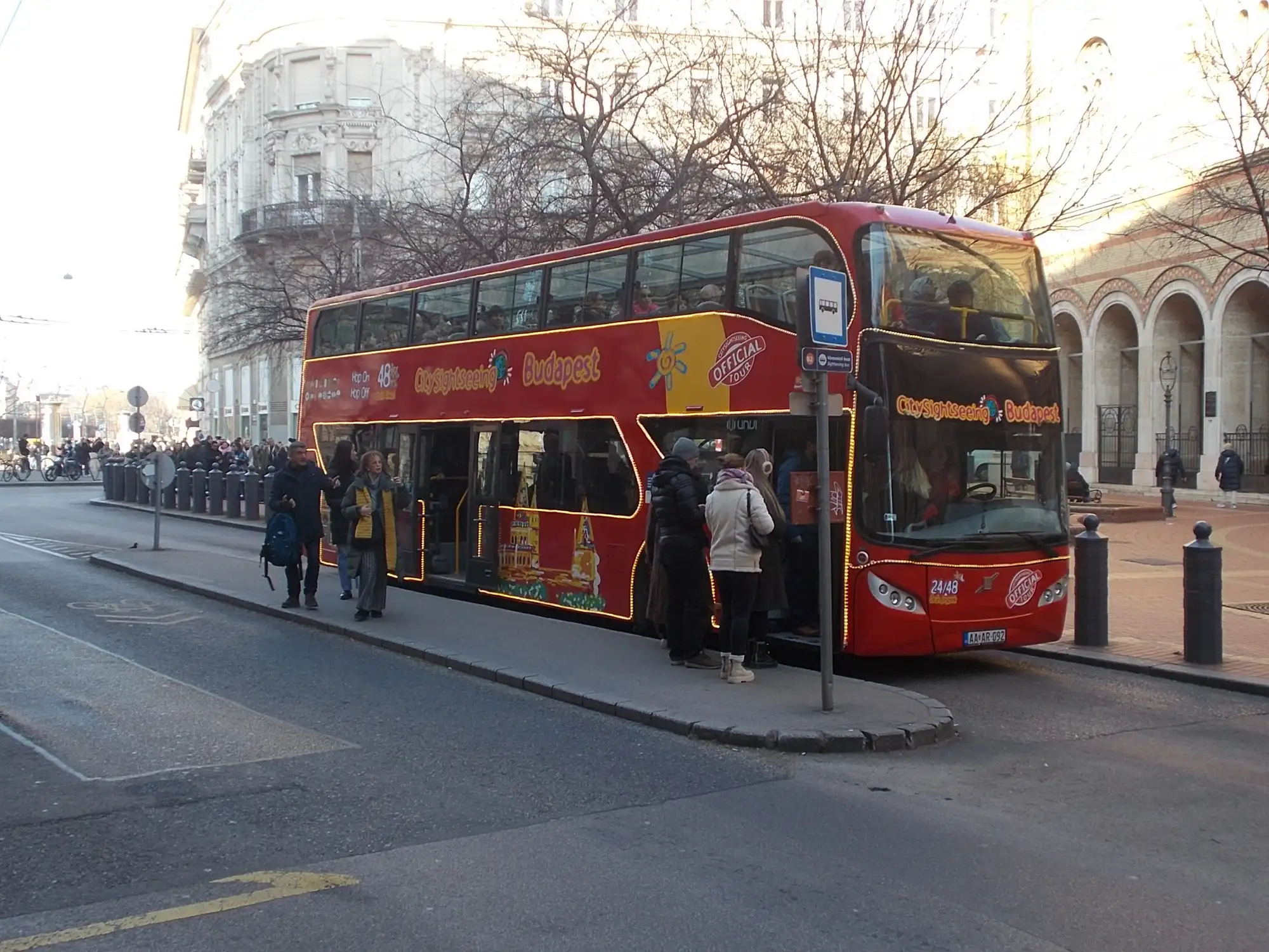 Passengers boarding a red City Sightseeing double-decker at the Dohány utca stop in Budapest in winter