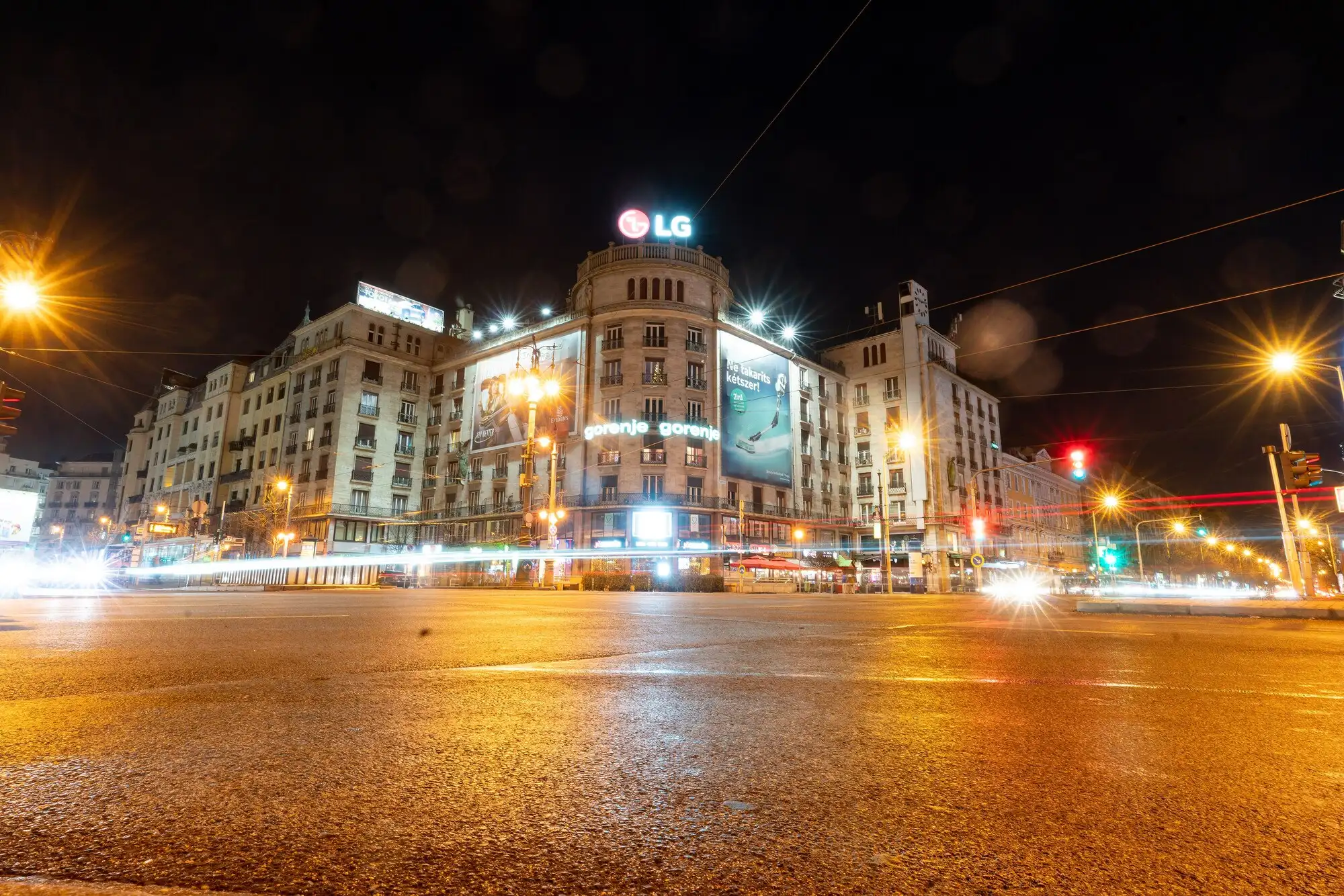 The restored Corvin Palace on Blaha Lujza tér in Budapest lit up at night, its neoclassical colonnade above the street