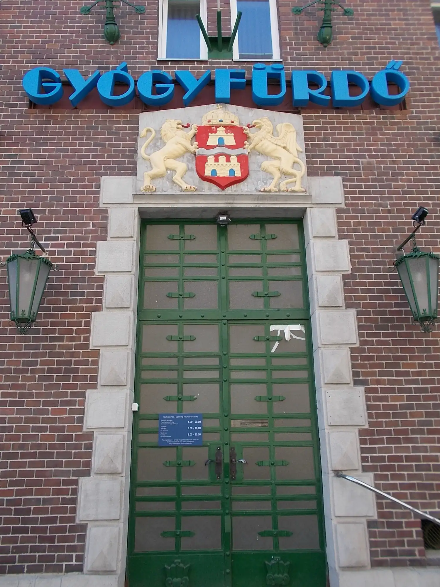 Brick entrance of Dandár Thermal Bath with the Budapest coat of arms above green iron doors