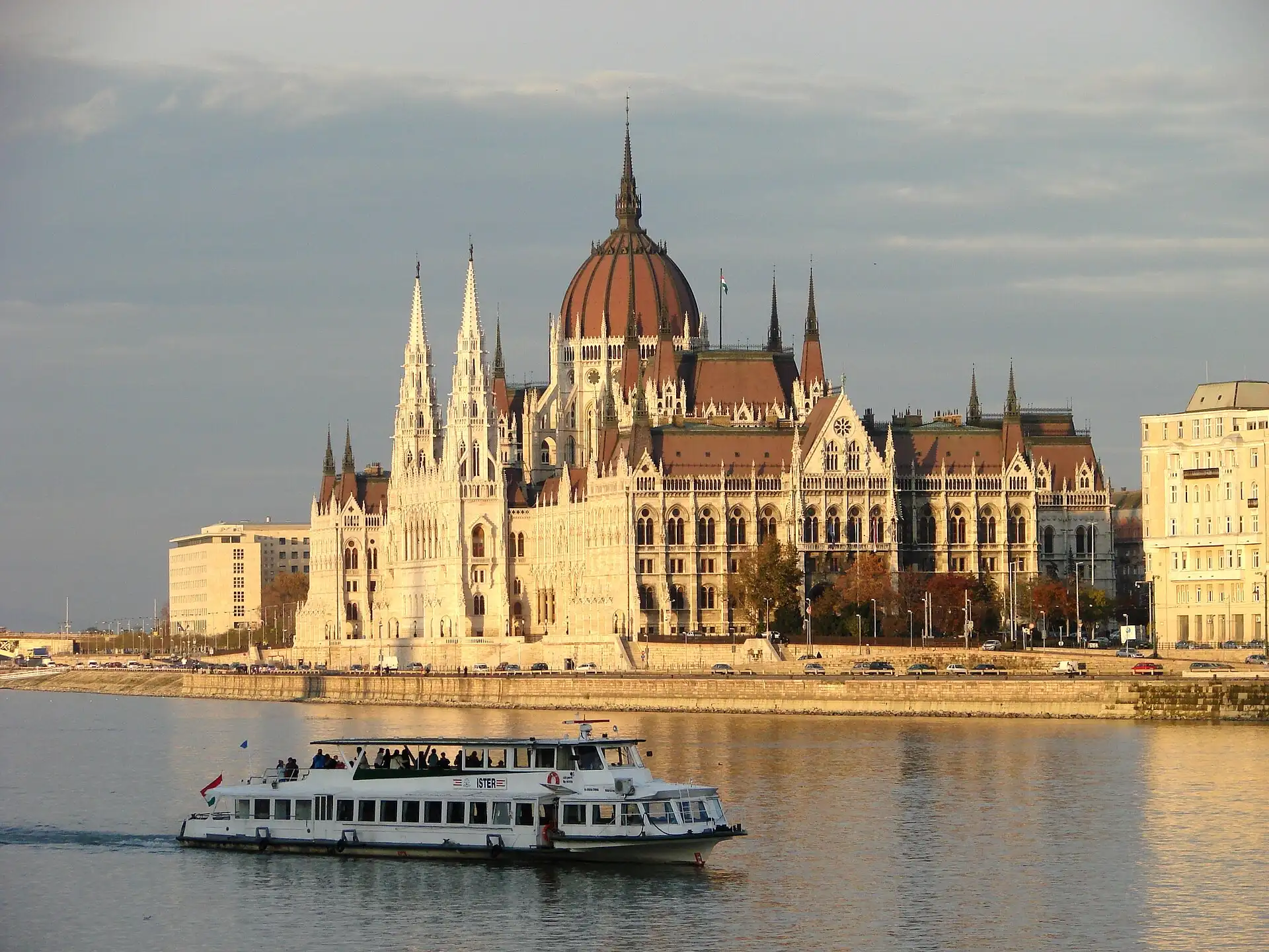 A white sightseeing boat passing the Hungarian Parliament on the Danube in evening light