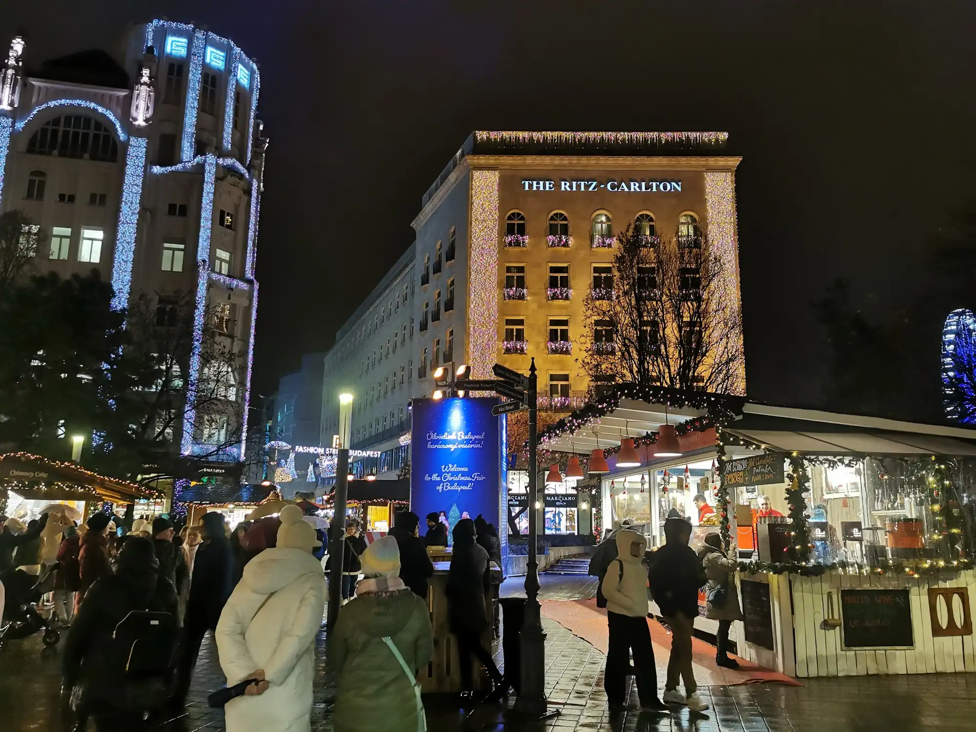 Christmas market stalls on Deák Ferenc tér at night, beneath illuminated buildings