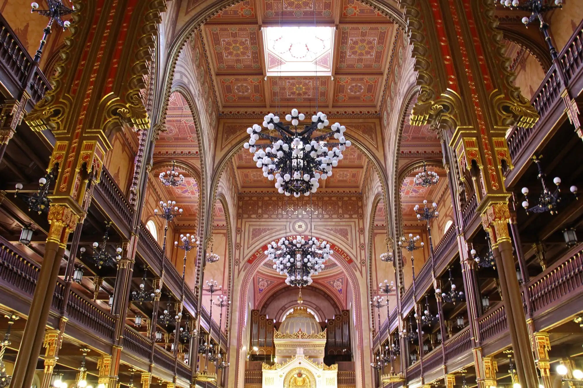 The main hall of the Dohány Street Synagogue, with its painted ceiling, chandeliers, two tiers of galleries and the white and gold Ark at the far end
