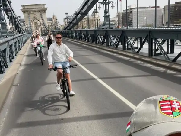 A group on e-bikes riding across the Chain Bridge in Budapest, with one of the bridge's stone towers ahead