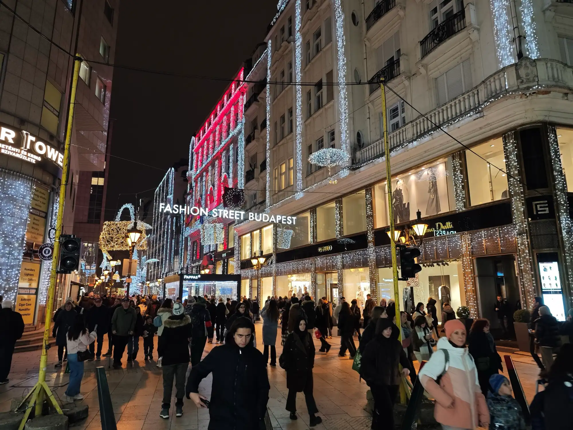 Deák Ferenc utca in Budapest at night, strung with Christmas lights under the Fashion Street Budapest sign, crowded with people
