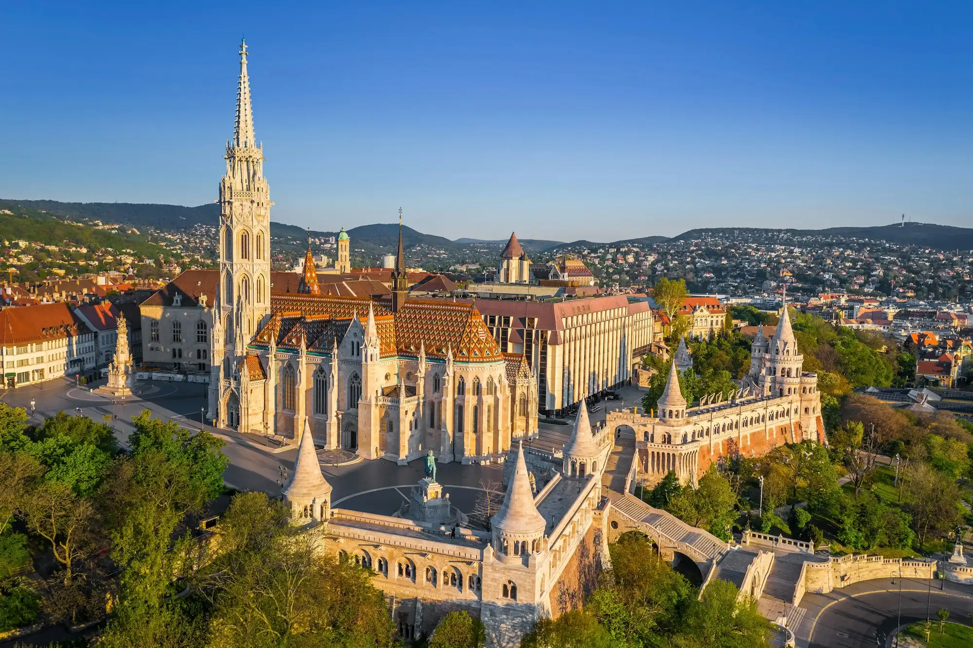 Fisherman's Bastion and Matthias Church seen from the air, with the arcades and turrets curving round the church above the wooded slope of Castle Hill