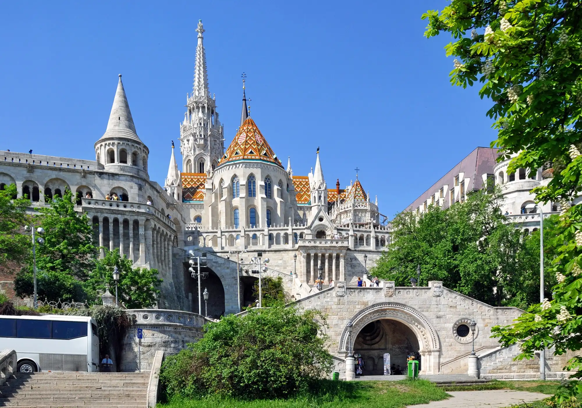 The Schulek staircase climbing from the road to the arcades and turrets of Fisherman's Bastion, with the spire and tiled roof of Matthias Church above