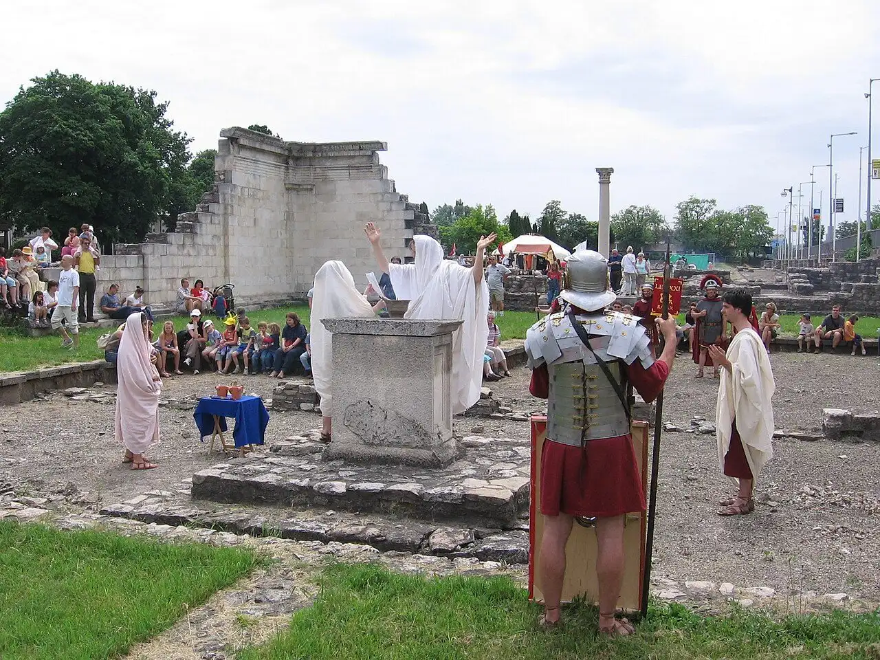 Re-enactors in togas performing a Roman ceremony at an altar during the Floralia festival at Aquincum, with a legionary in armour and visitors watching from the ruins