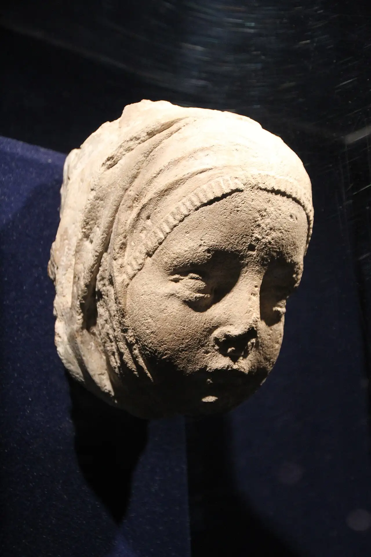 A carved stone head from the 1974 Gothic sculpture find, lit in a display case at the Budapest History Museum