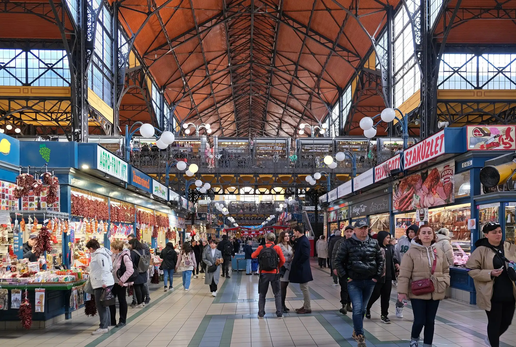The ground floor of the Great Market Hall in Budapest packed with shoppers at midday, seen from the gallery