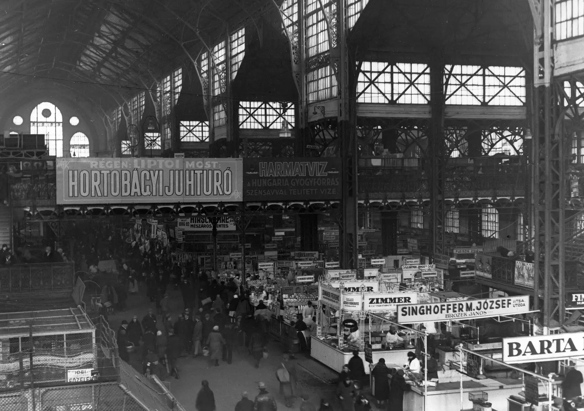 The interior of the Central Market Hall in Budapest around 1930, with advertising signs hung above the stalls