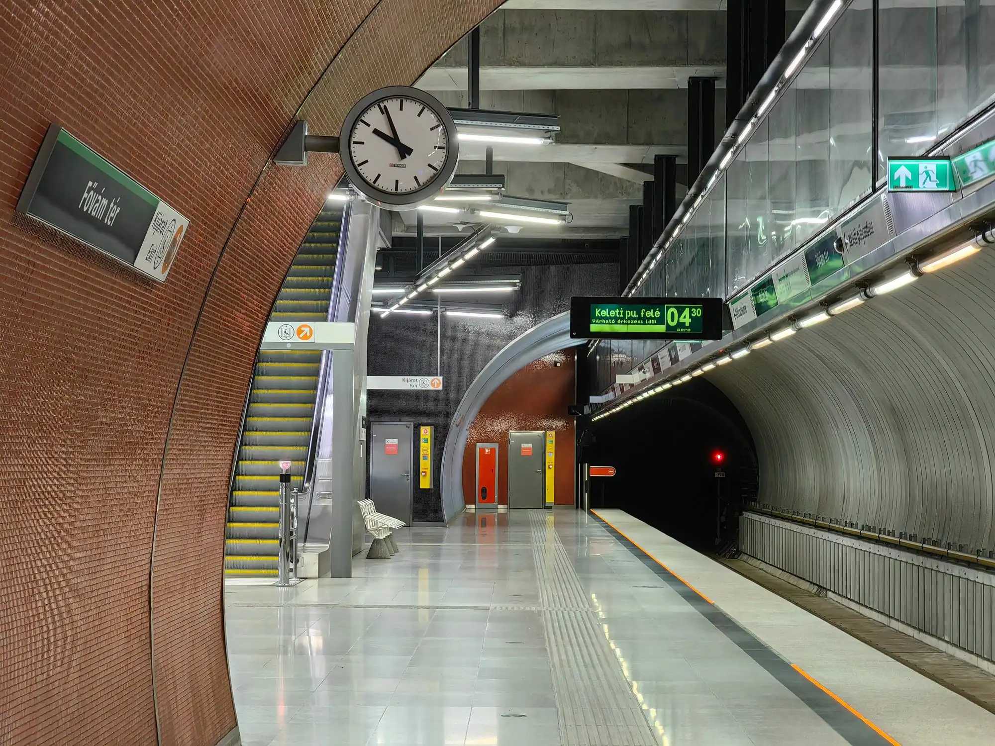 The platform at Fővám tér station on metro line M4 in Budapest, with the station name on the brick wall and escalators up to the square