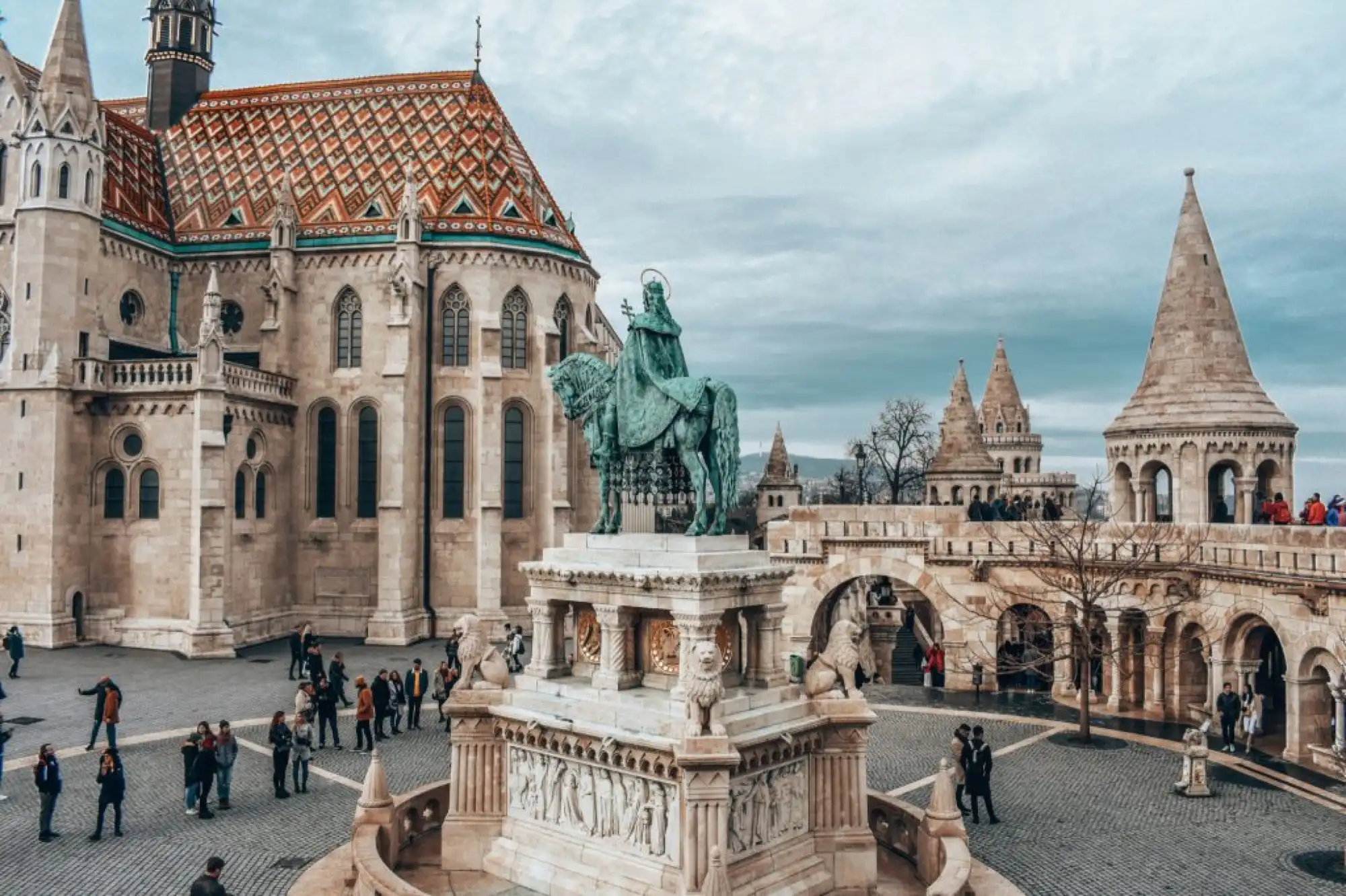 The diamond-patterned Zsolnay roof and apse of Matthias Church beside the St Stephen statue and the turrets of Fisherman's Bastion