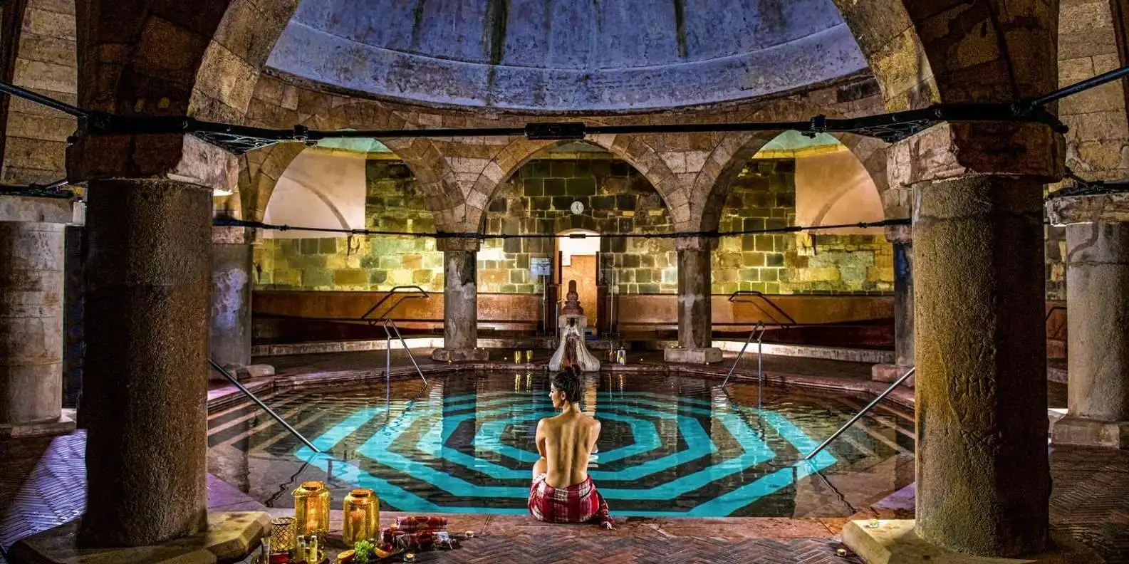 The octagonal pool of the Turkish bath at Rudas, under a stone dome on pillars, with a bather sitting at the edge