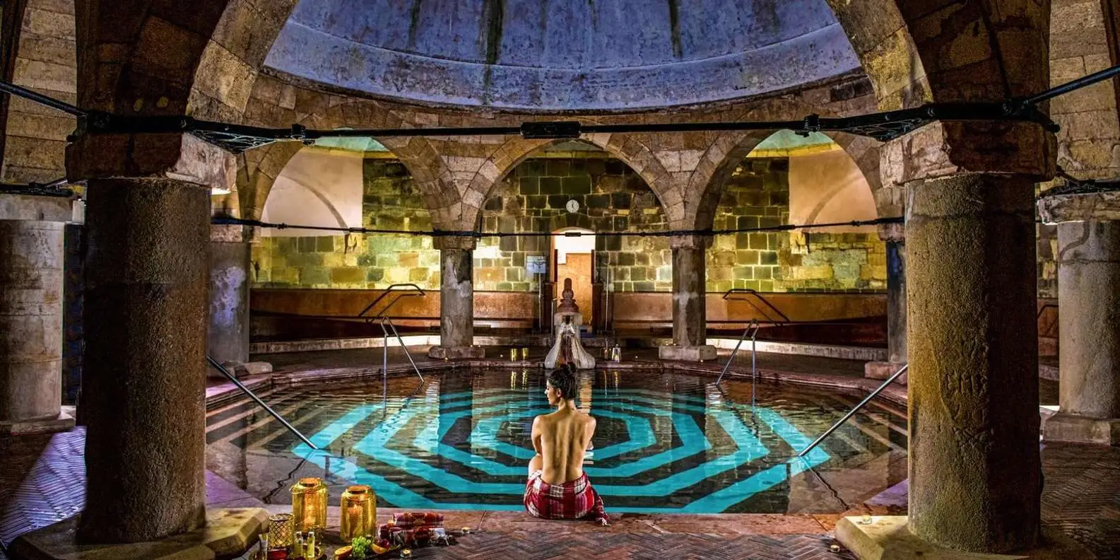 The octagonal pool under the Ottoman dome of the Turkish bath at Rudas Thermal Bath, with a bather sitting on the steps