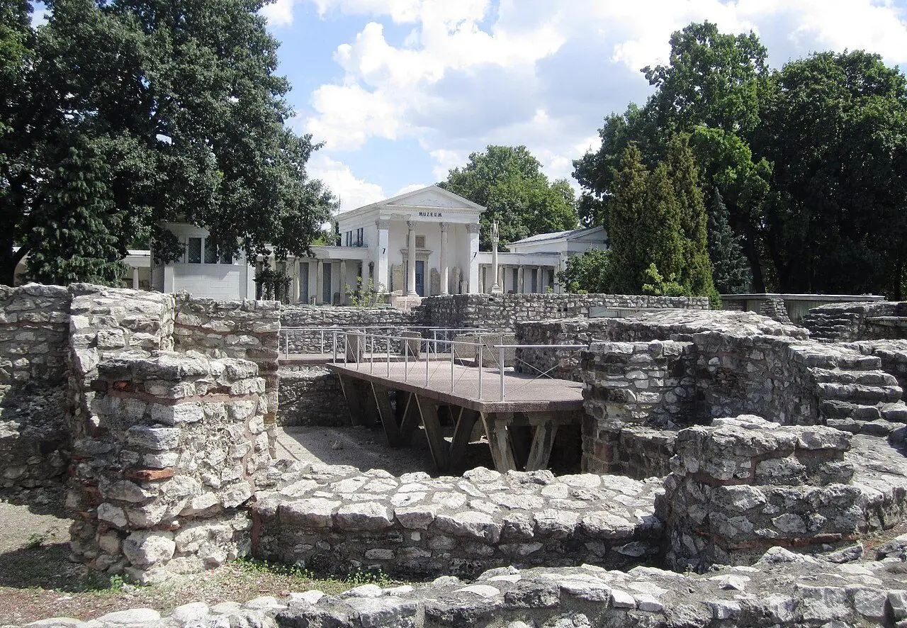 Roman walls in the Aquincum Archaeological Park, with the neoclassical museum building of 1894 behind them