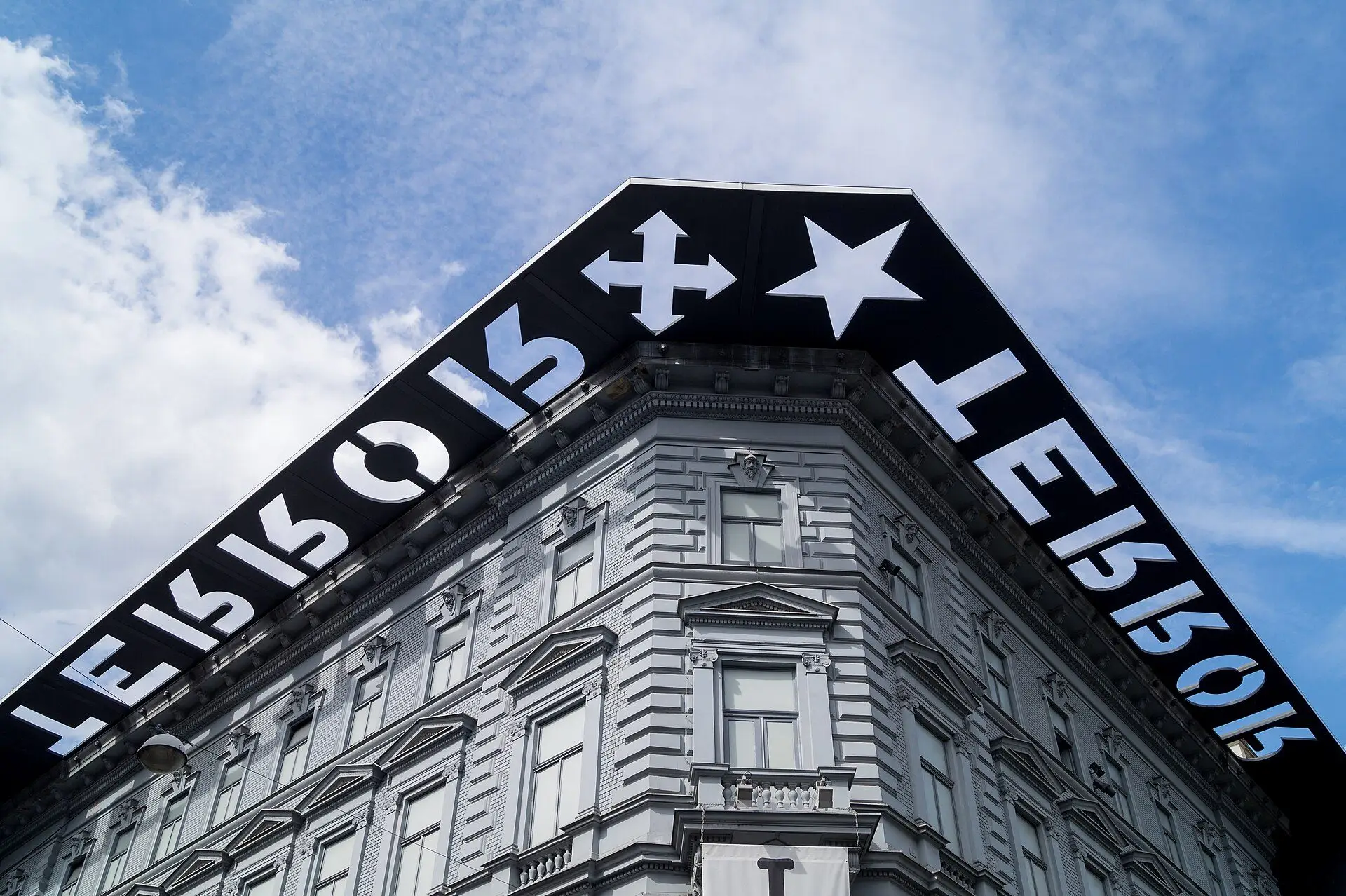 The corner of the House of Terror Museum on Andrássy út, under the black entablature cut with the word TERROR, the Arrow Cross and the star