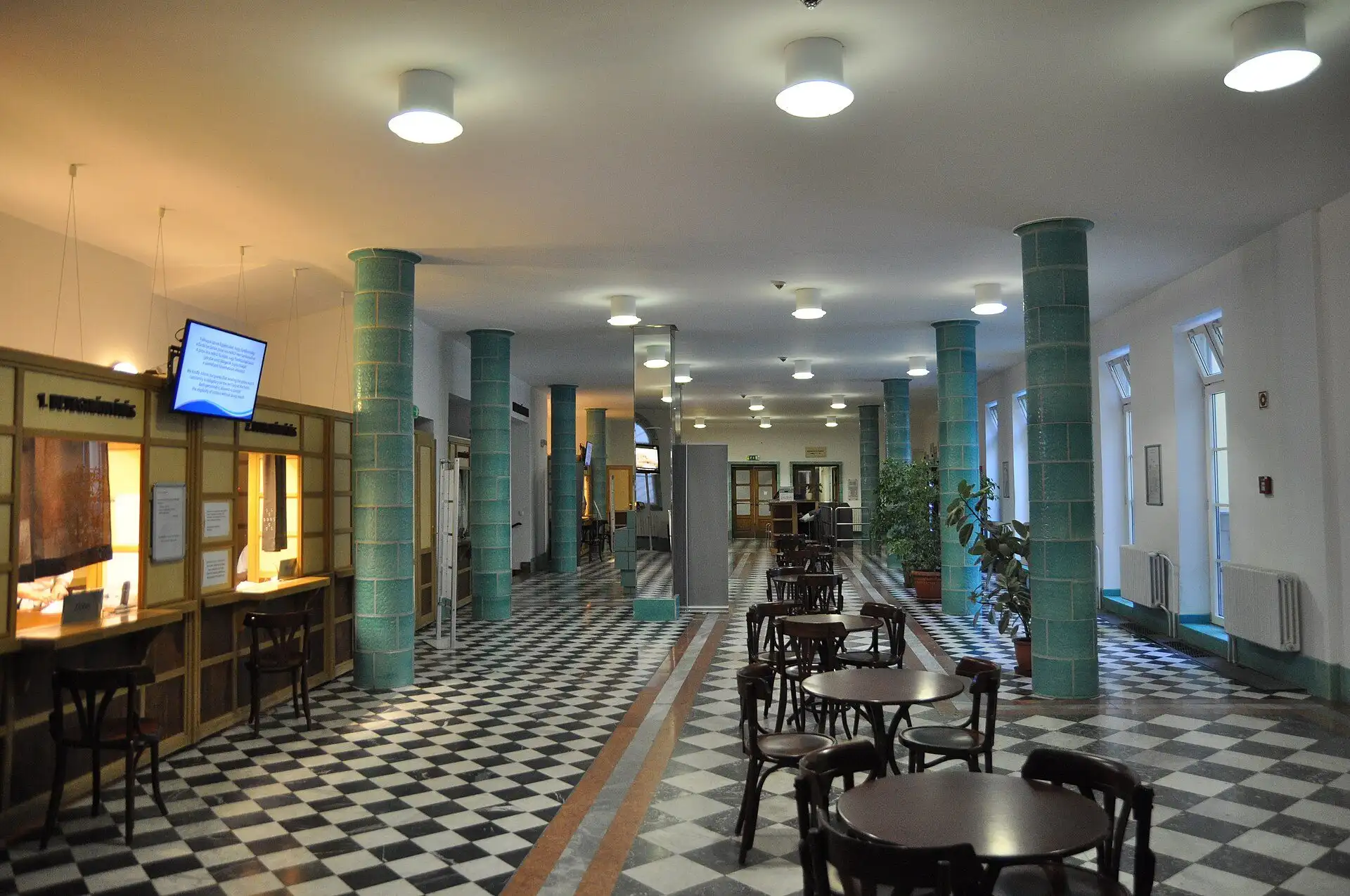 The entrance hall at Lukács Thermal Bath, with ticket windows, green tiled columns and a chequerboard floor