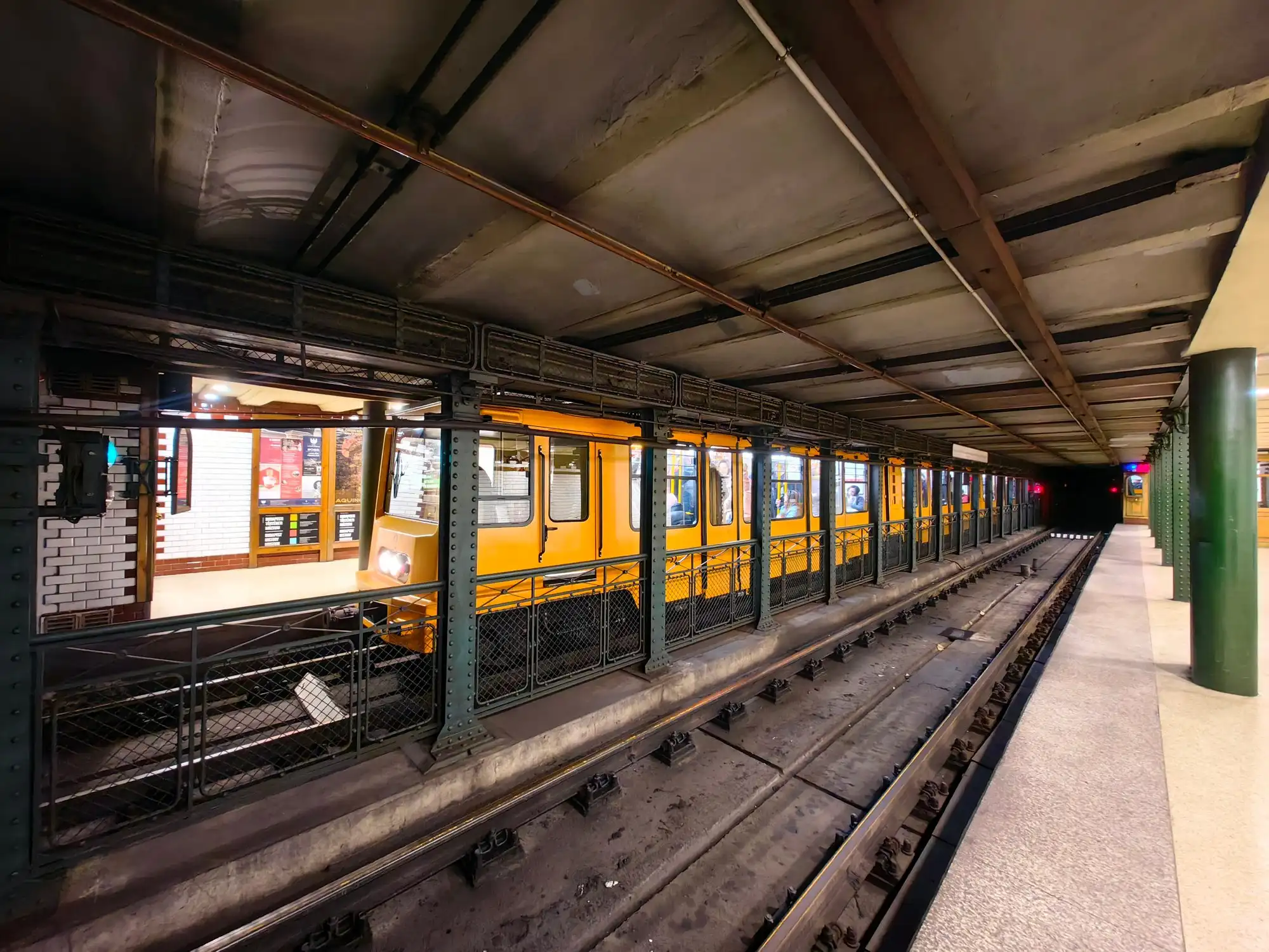 A short yellow Millennium Underground train at the platform of Kodály körönd station on Budapest's M1 line