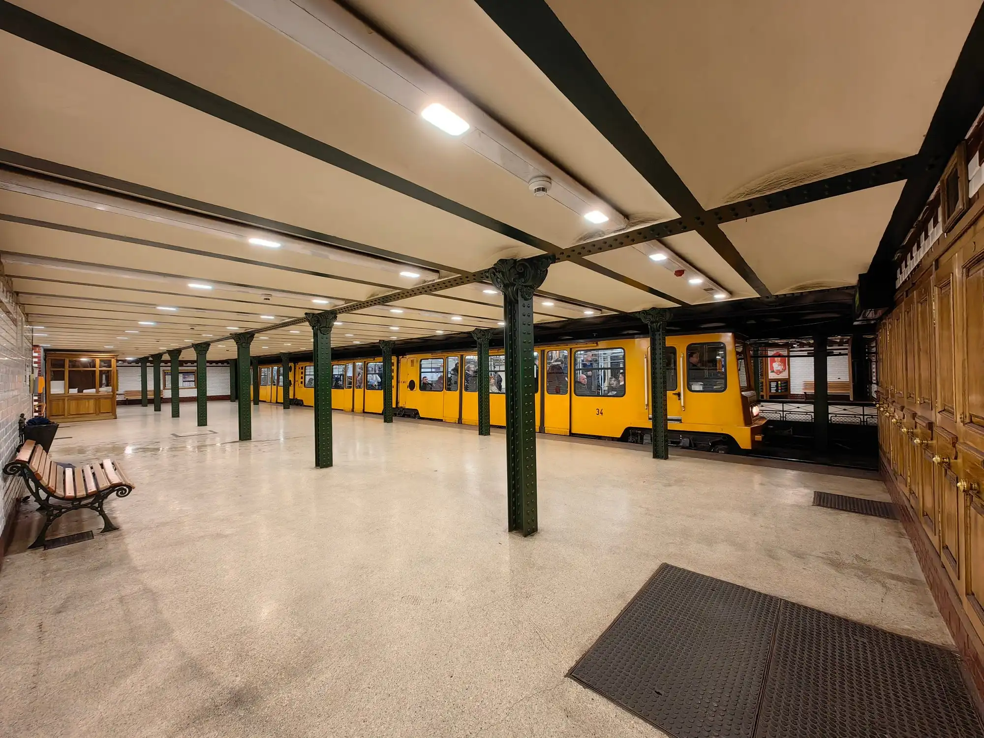 A yellow Millennium Underground train standing at the timber-panelled platform of Oktogon station on the M1 line in Budapest