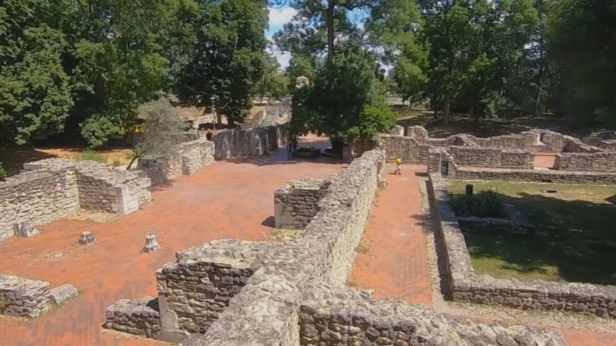 Ancient stone ruins with pathways and trees on Margaret Island in Budapest.