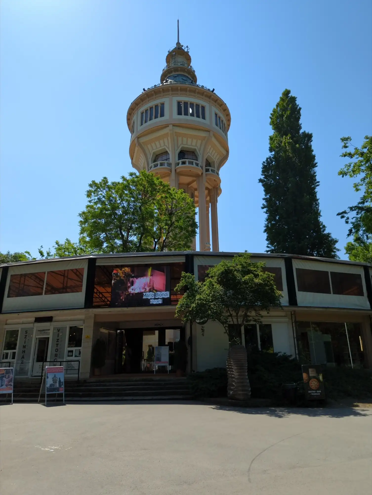 The Margaret Island Water Tower rising above the trees behind the entrance to the island's open-air theatre, on a sunny day