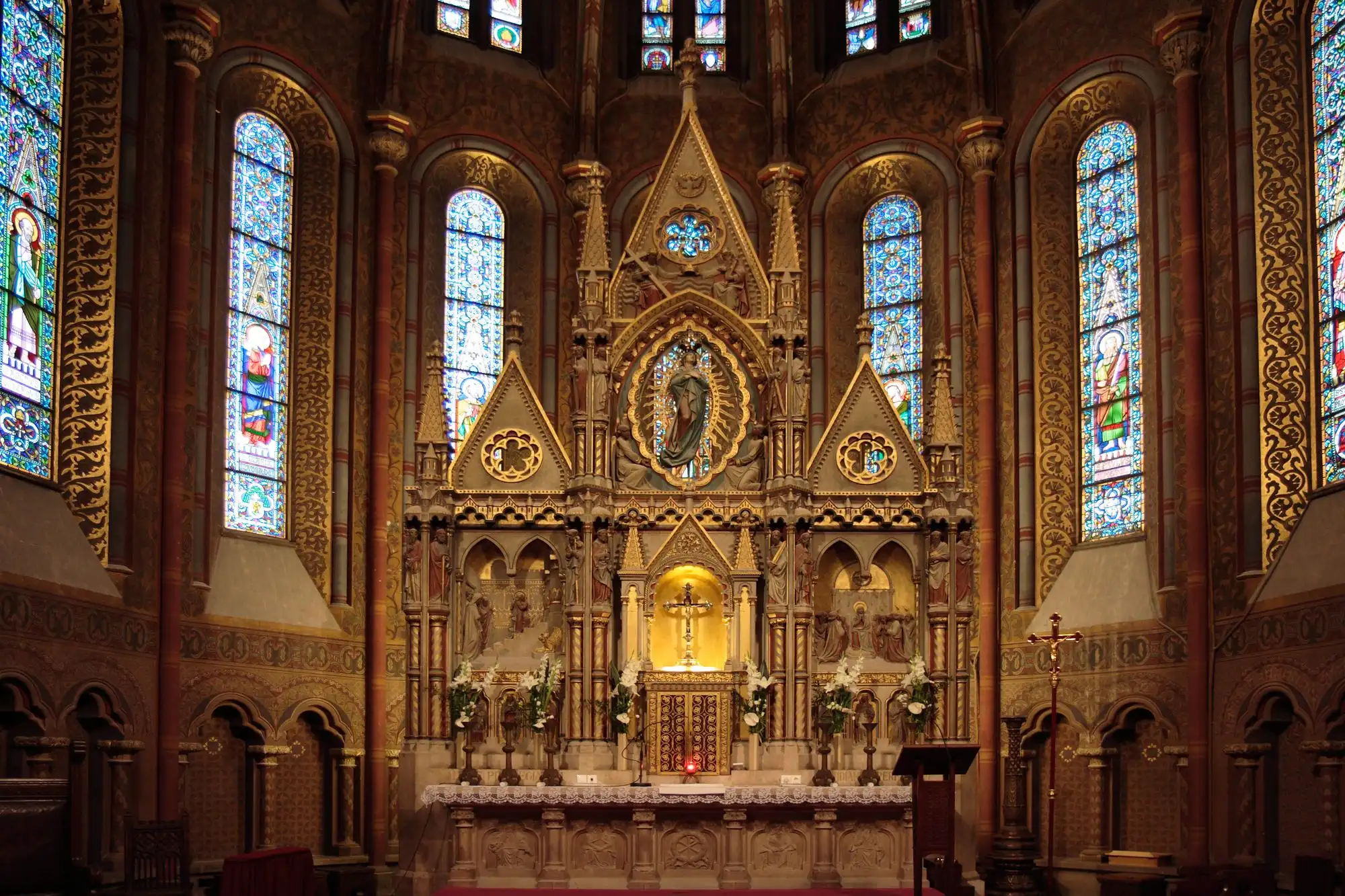 The main altar of Matthias Church, with the crowned statue of the Virgin in a Gothic canopy between tall stained-glass windows