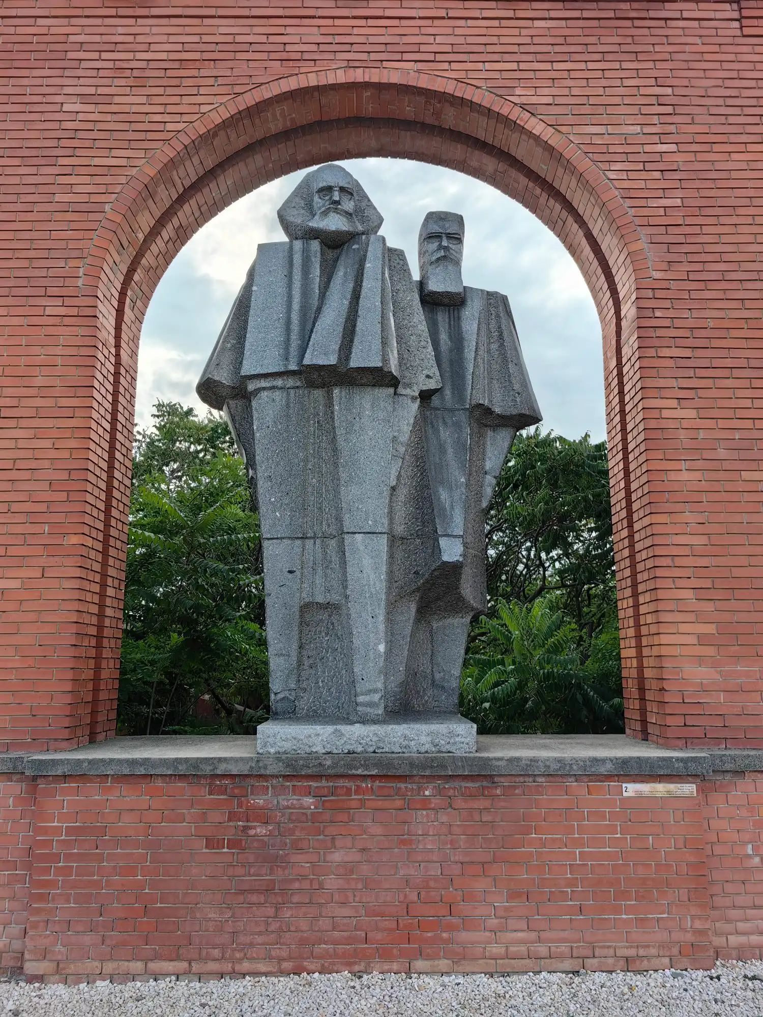 György Segesdi's stone statue of Marx and Engels in an arch of the brick entrance facade of Memento Park