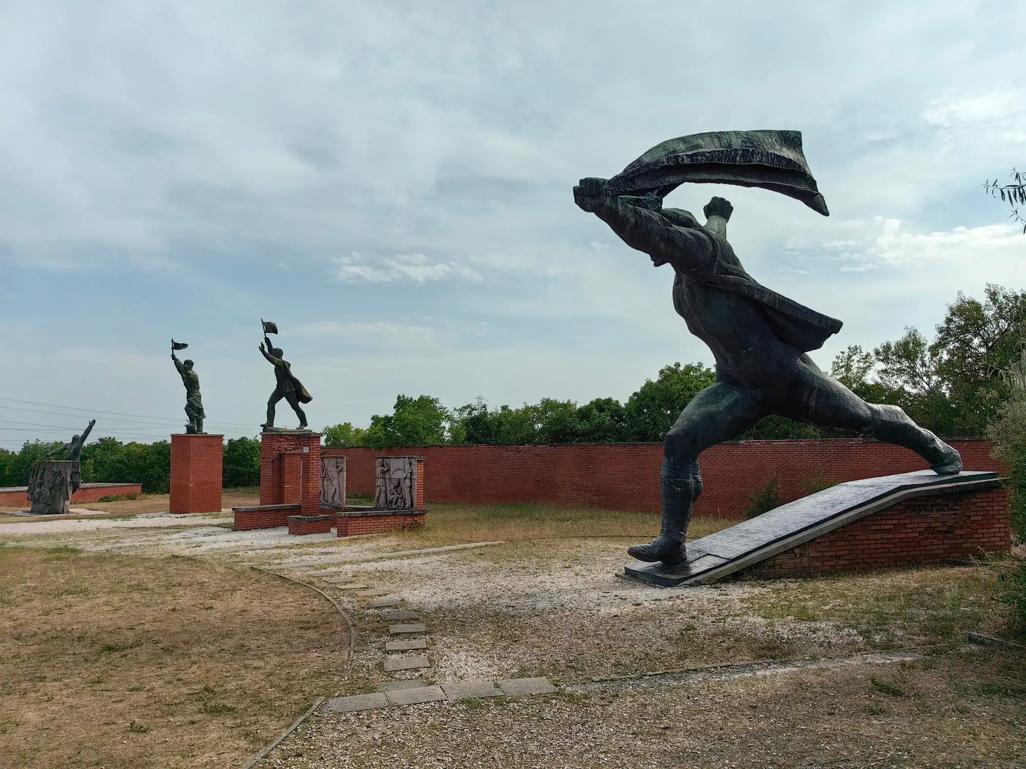 István Kiss's Republic of Councils monument at Memento Park, a running figure with a flag, with other statues behind