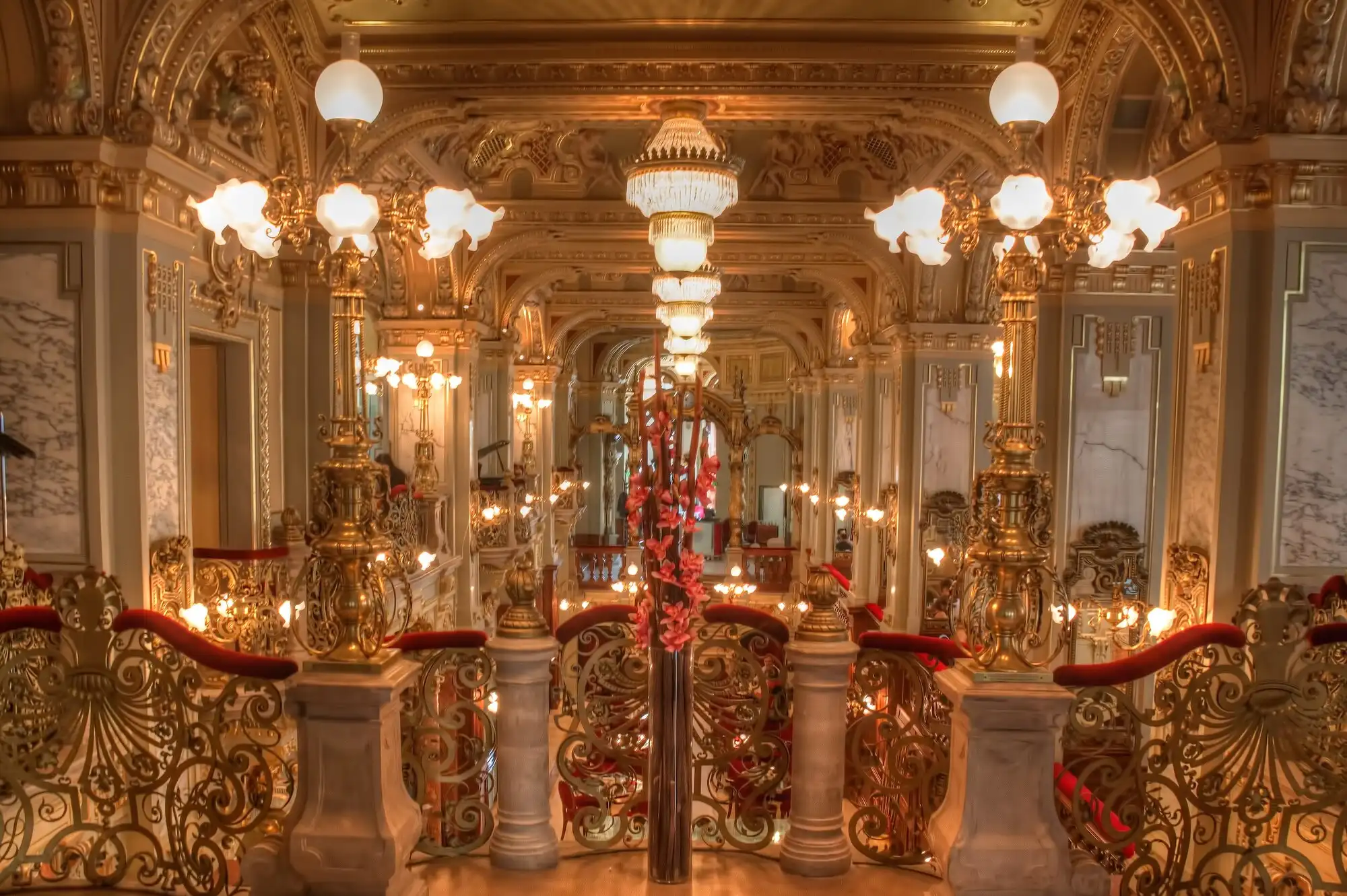 The gilded interior of the New York Café in Budapest, with marble columns, mirrors, chandeliers and tiers of lamps above the balustrades
