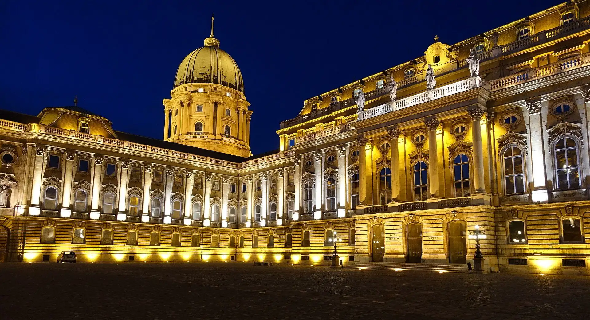 The floodlit river facade and dome of Buda Castle at night