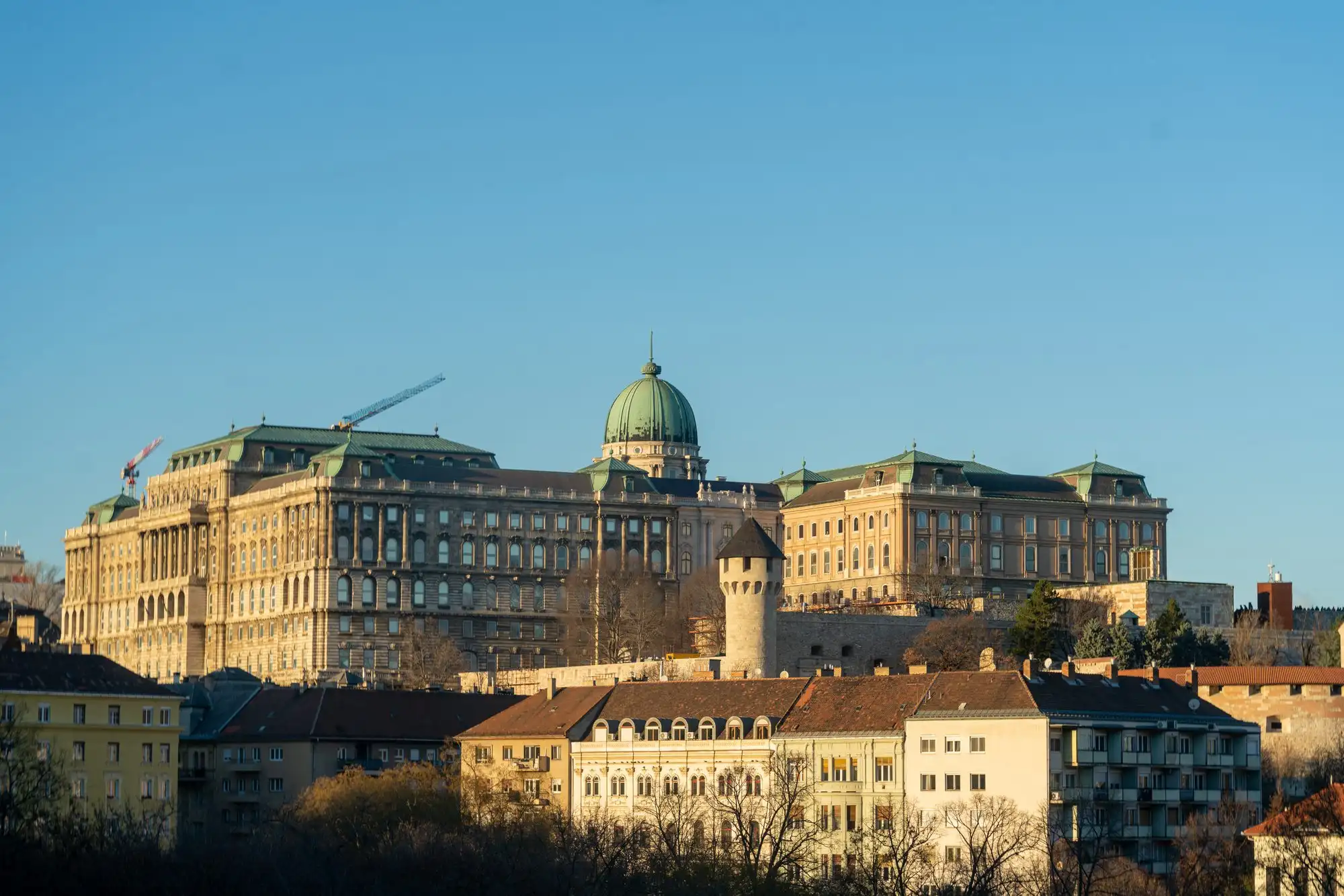 Buda Castle's Royal Palace seen from across the Danube in December 2025, with construction cranes over the northern wing