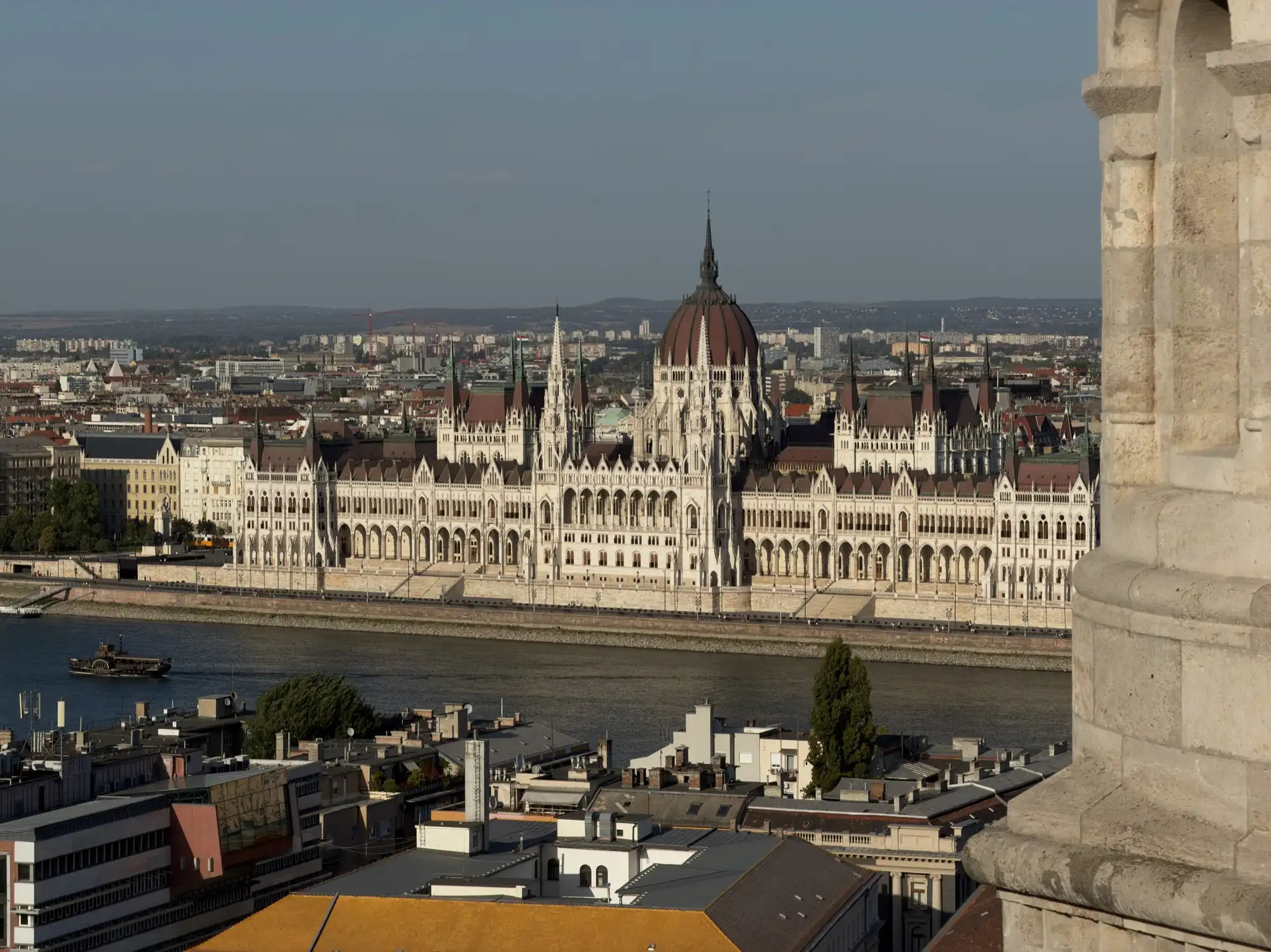 The Hungarian Parliament on the far bank of the Danube, seen from the Buda side with the edge of a stone turret on the right