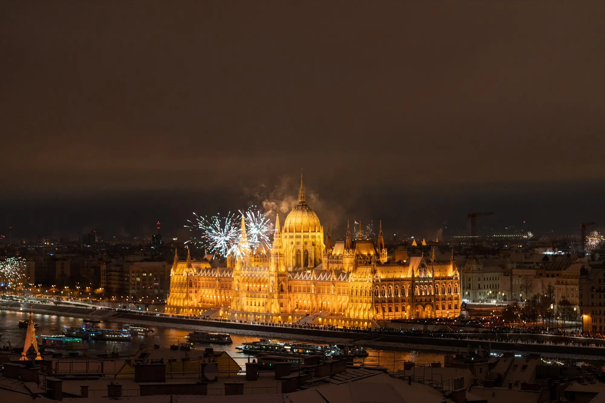 Fireworks bursting beside the dome of the floodlit Hungarian Parliament across the Danube just after midnight on New Year's Day