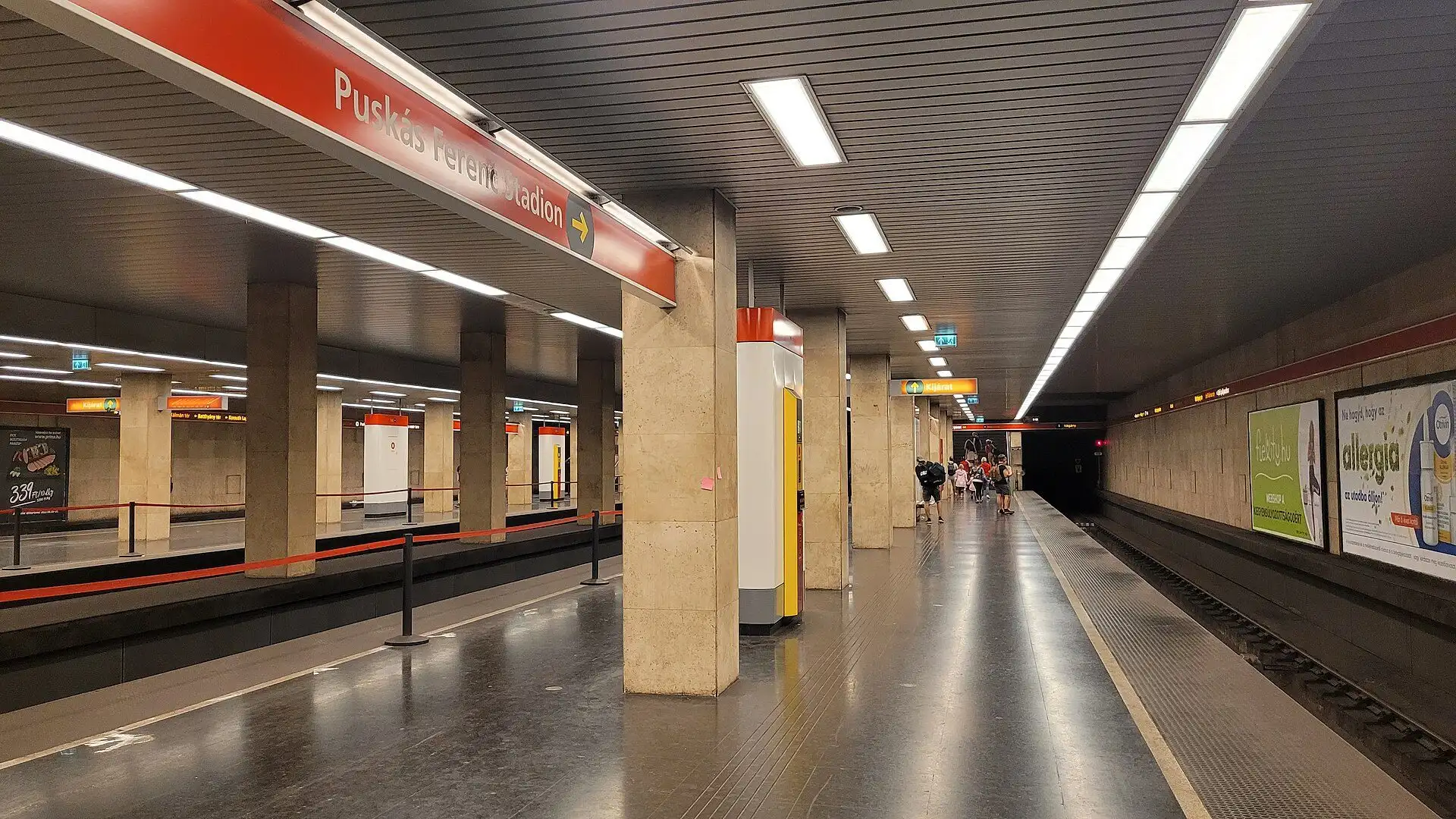 The platform of Puskás Ferenc Stadion metro station on the M2 line, with its red-tiled pillars and the station name on the wall