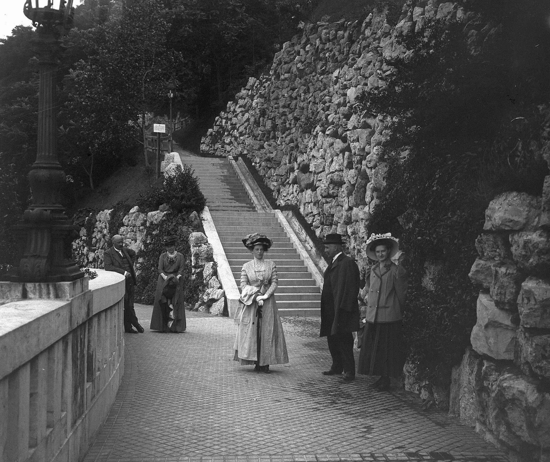 Edwardian visitors standing on the stone steps beside the artificial waterfall below the St Gellért monument, photographed in 1910