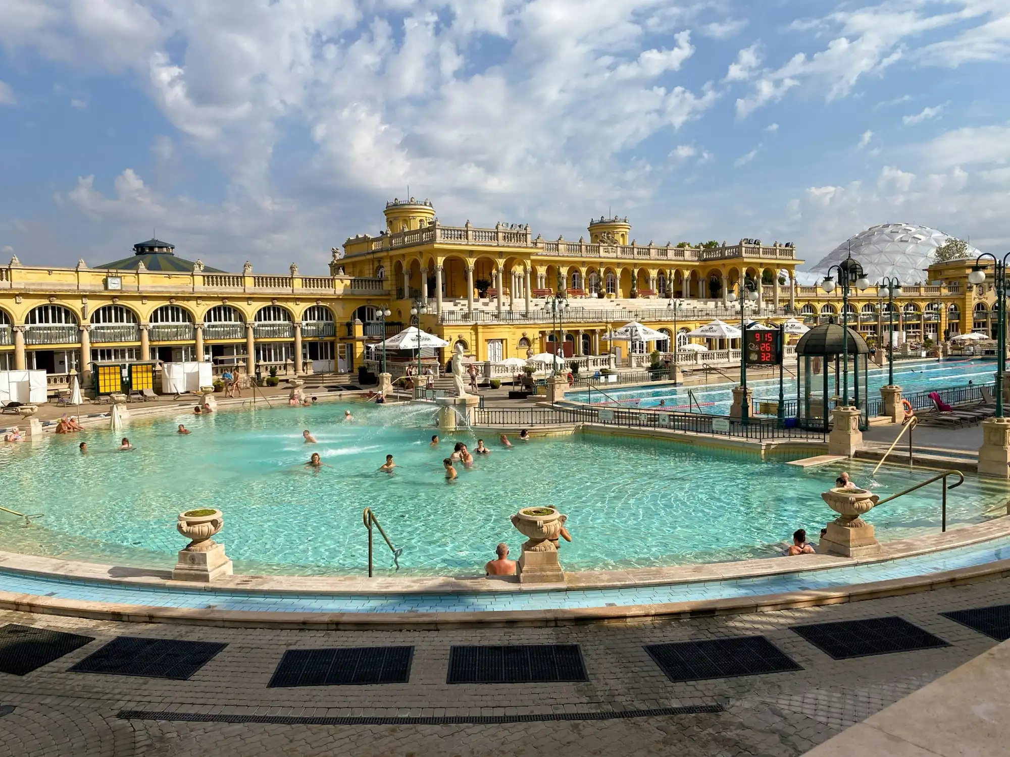 Széchenyi Thermal Bath outdoor pools with bathers in winter, snow on the Neo-Baroque dome behind