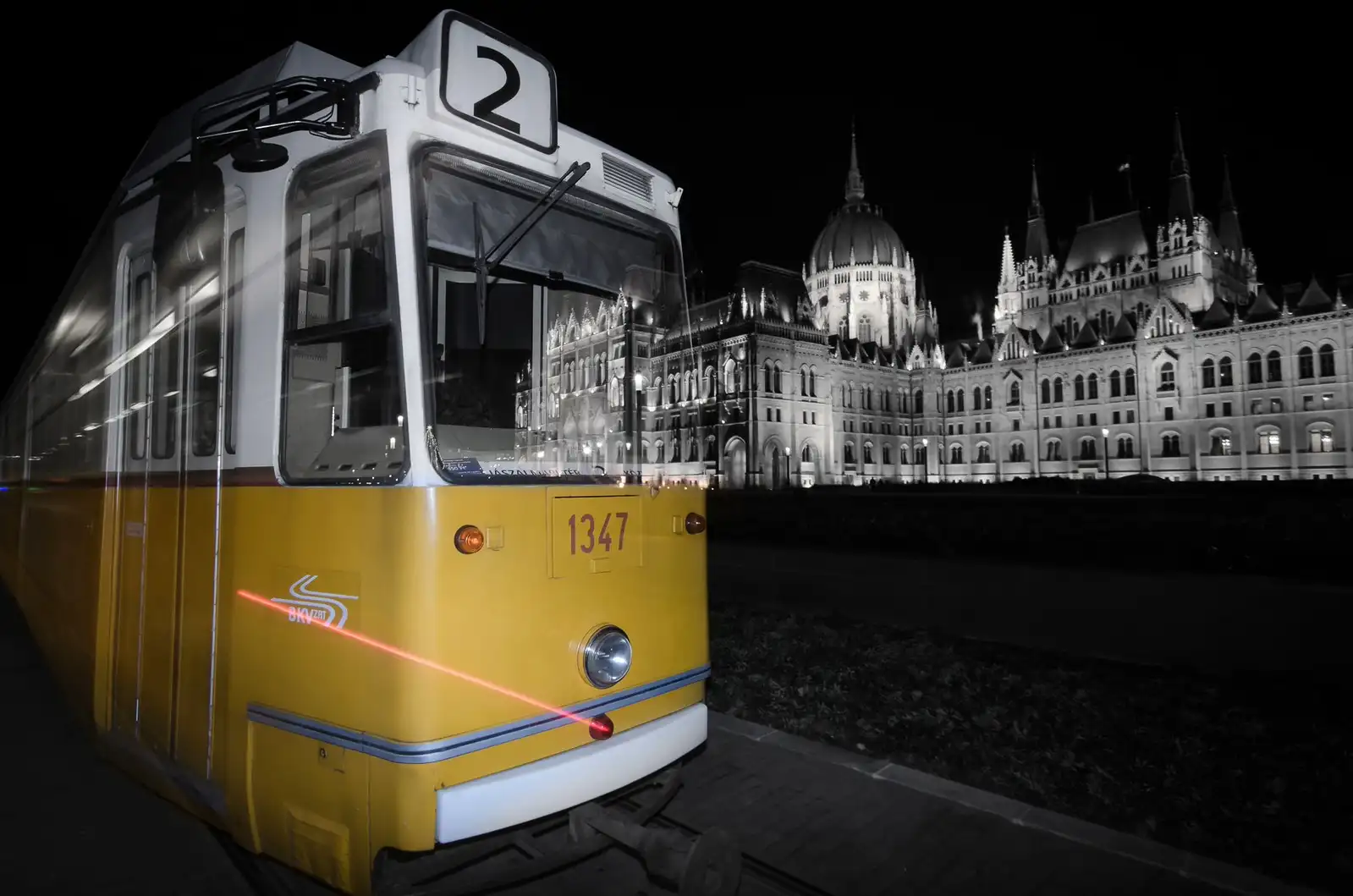 A yellow tram 2 at Kossuth Lajos tér at night, with the floodlit Parliament behind it