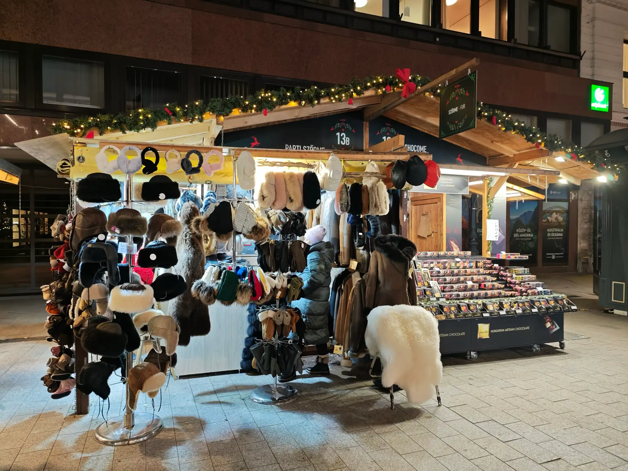 A Christmas market stall on Vörösmarty tér hung with sheepskin and fur hats, with a white sheepskin on a stand in front